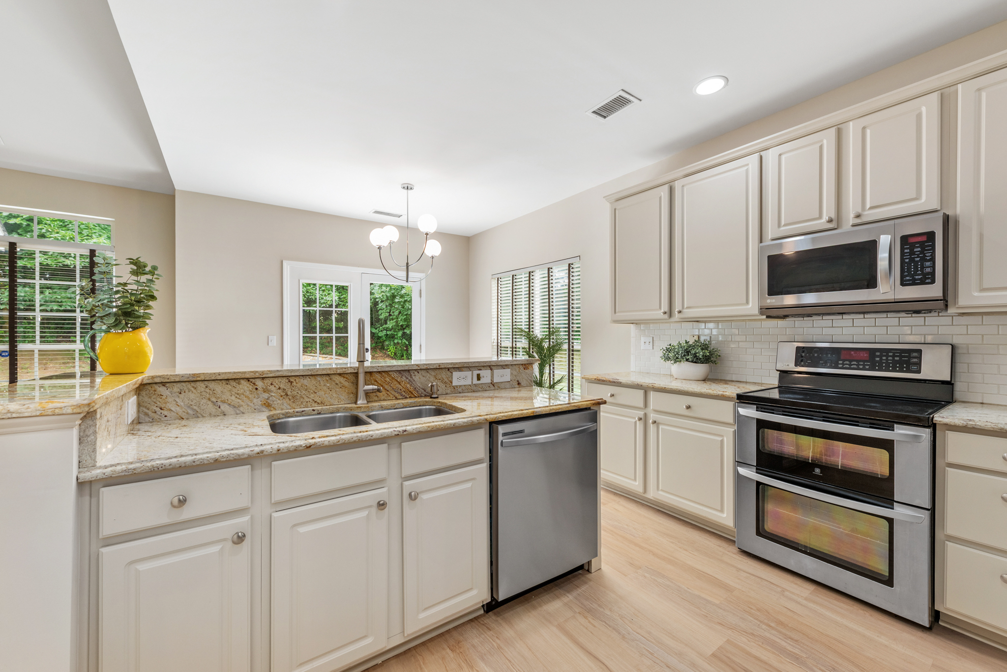 Transitional kitchen with beige cabinetry, granite countertops, and white subway tile backsplash
