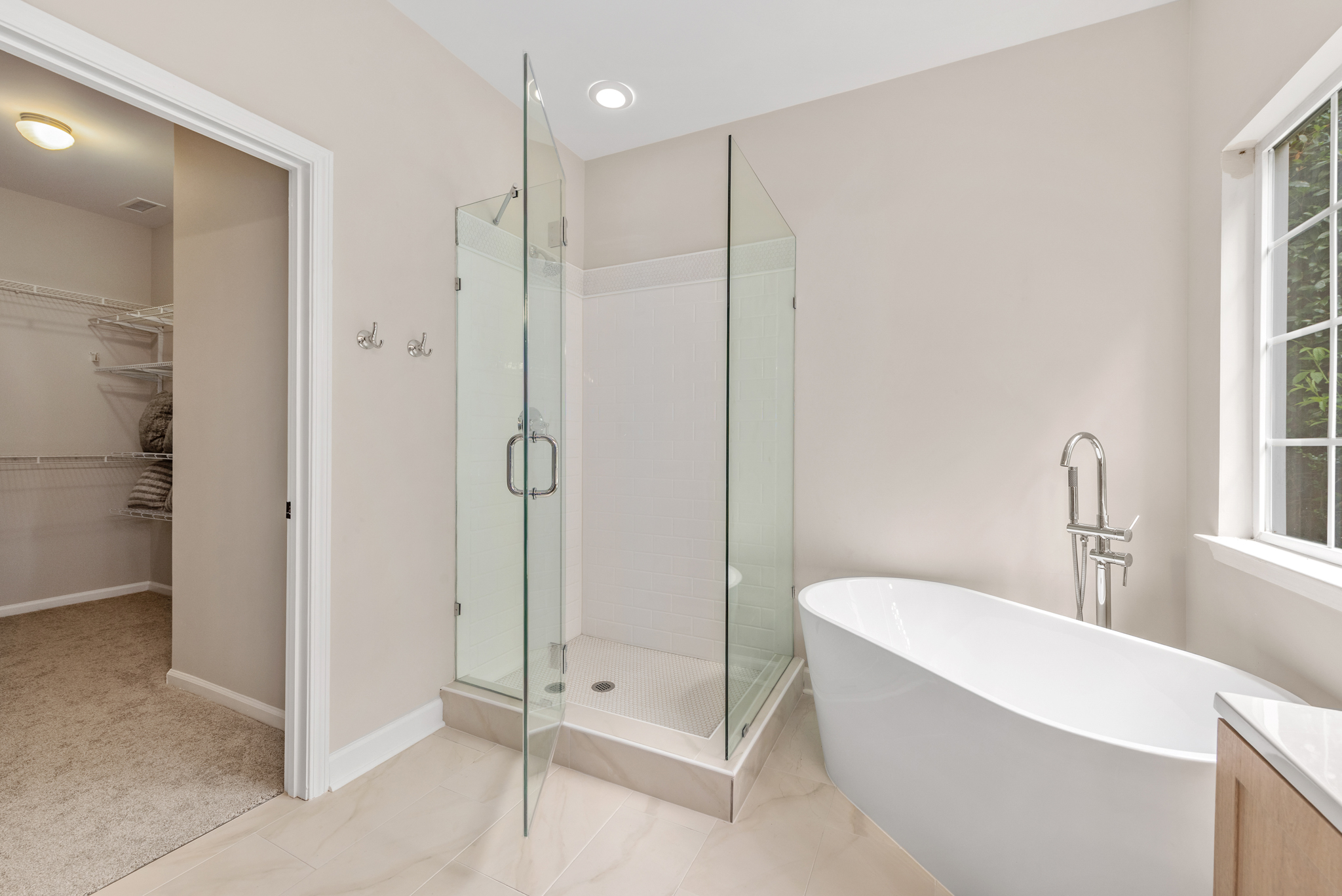 Primary bathroom with freestanding soaking tub and frameless glass shower