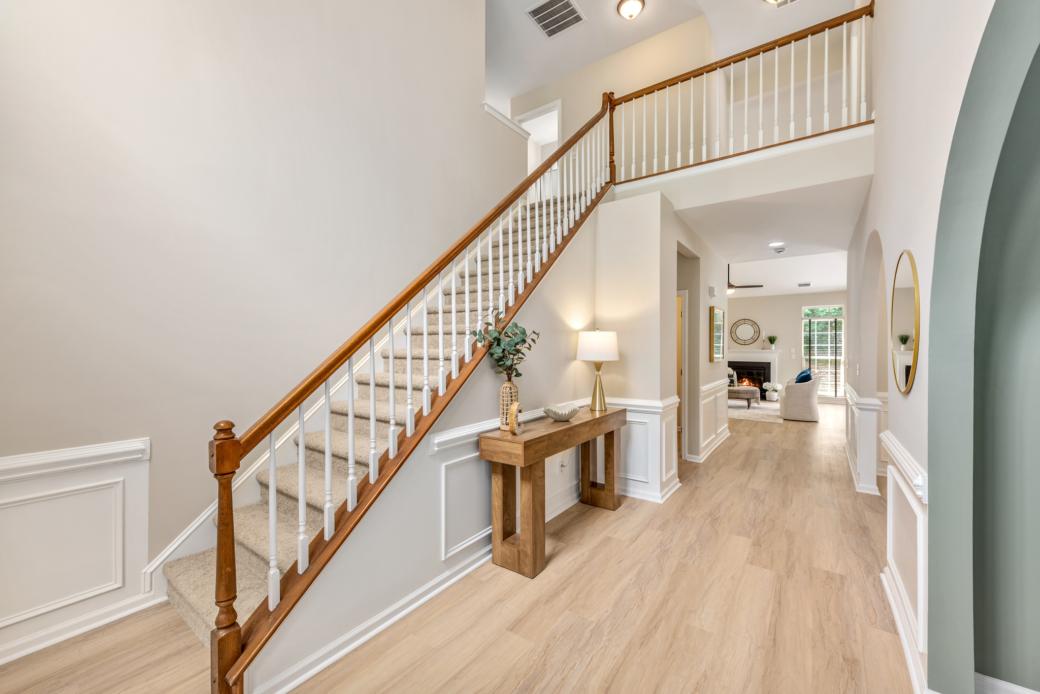 Entry hallway with staircase, light wood-look floors, and white wainscoting