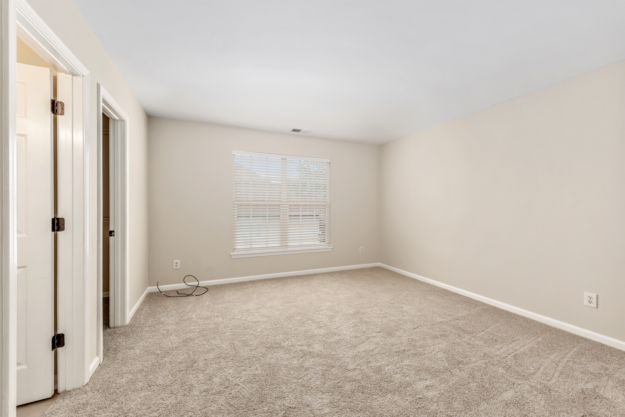 Vacant bedroom with neutral beige walls and natural light