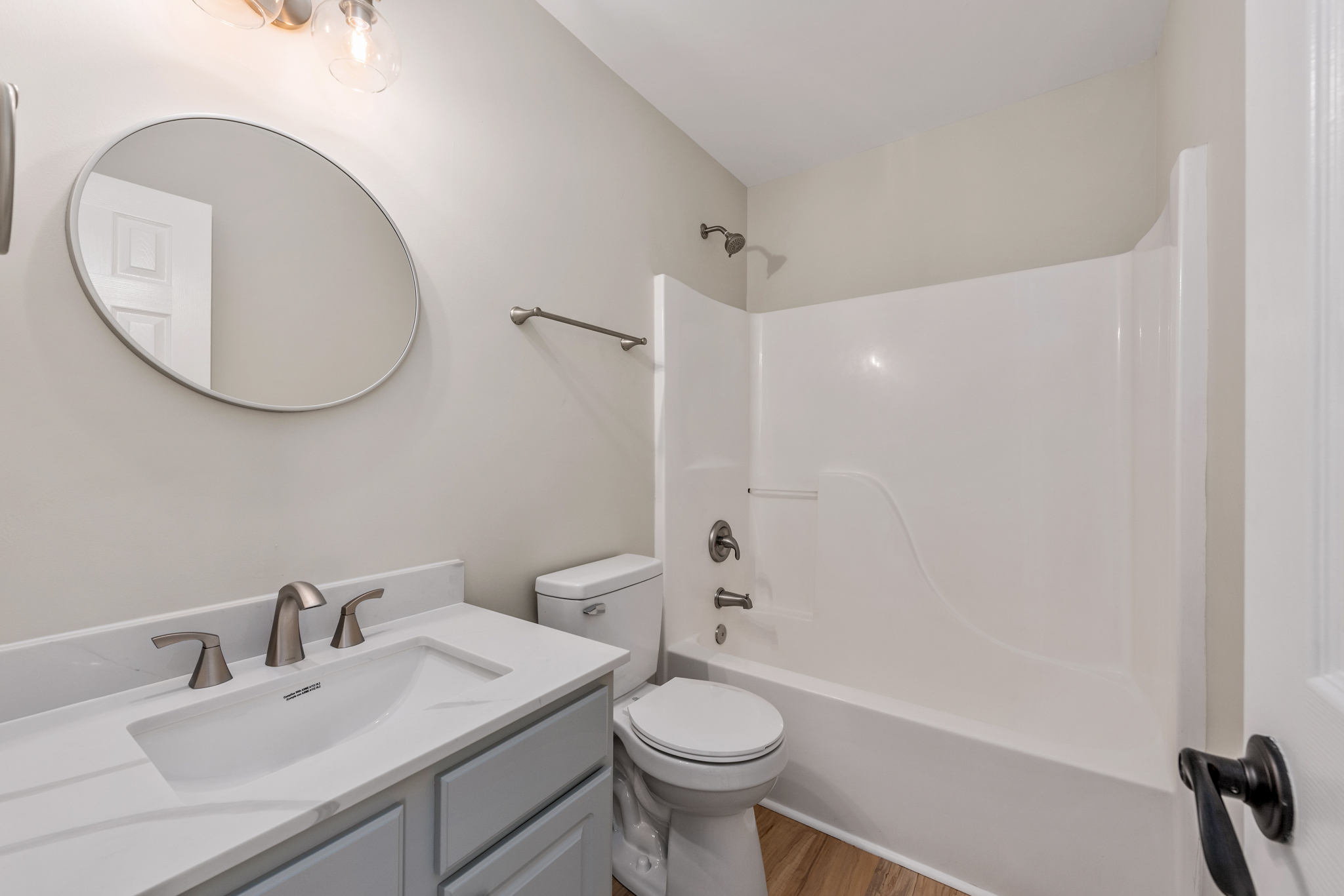 Full bathroom with light grey vanity, white countertop, and tub/shower surround