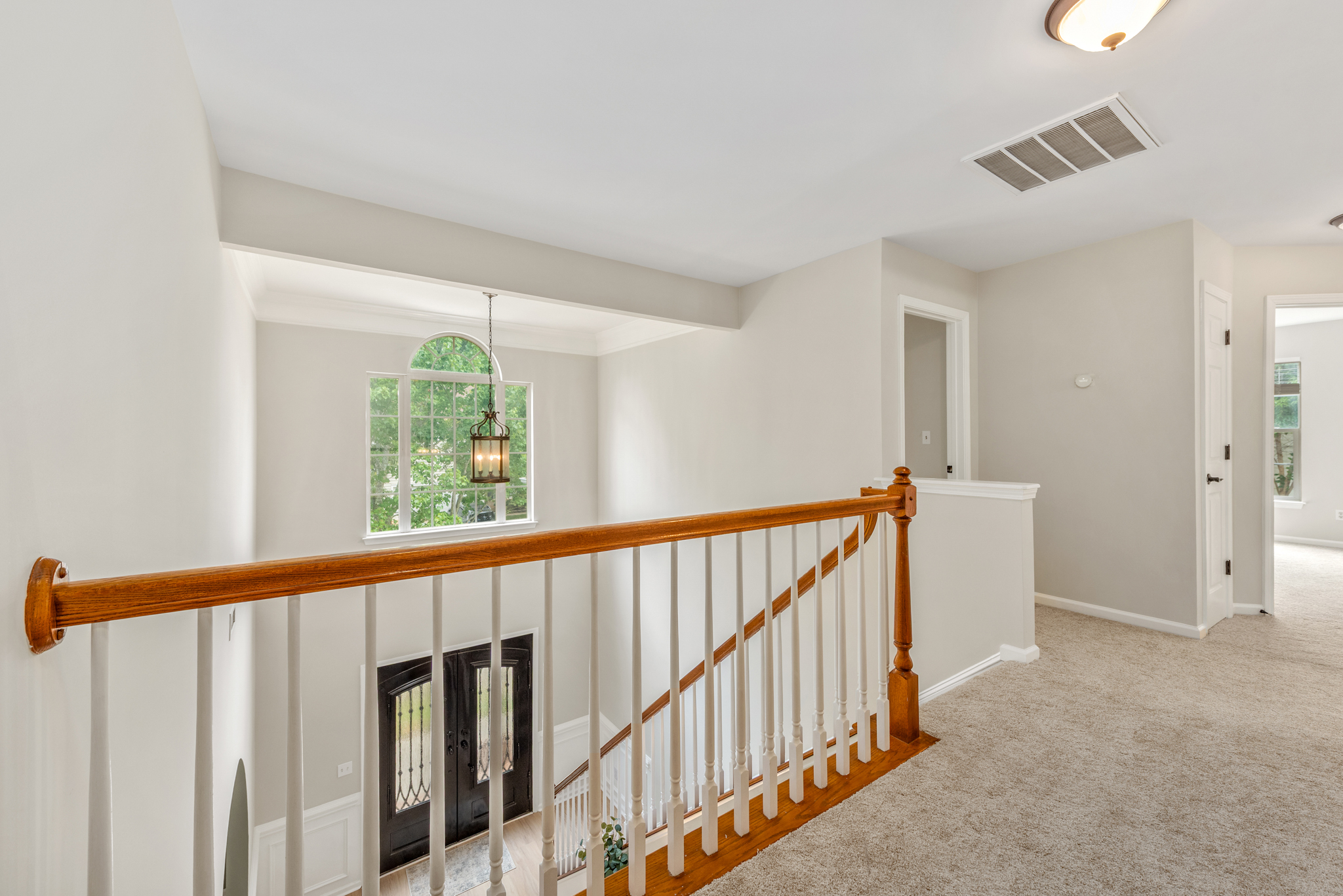 Second-floor landing overlooking the foyer with arched entryway window