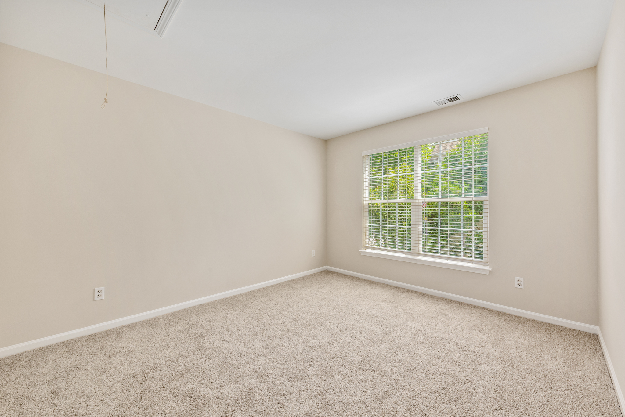Vacant secondary bedroom with double windows and natural daylight