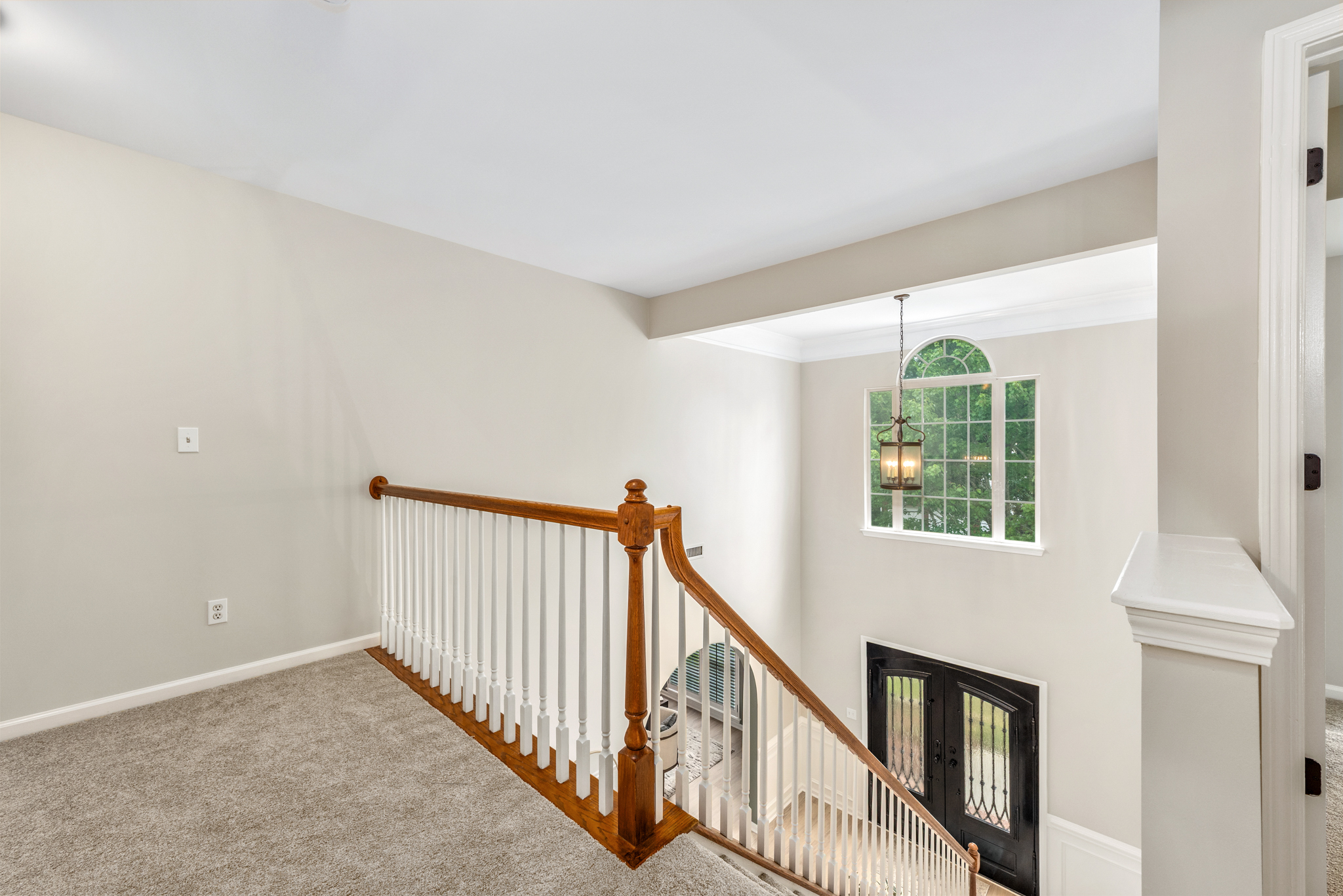 Upper-level landing with hanging pendant light and arched window