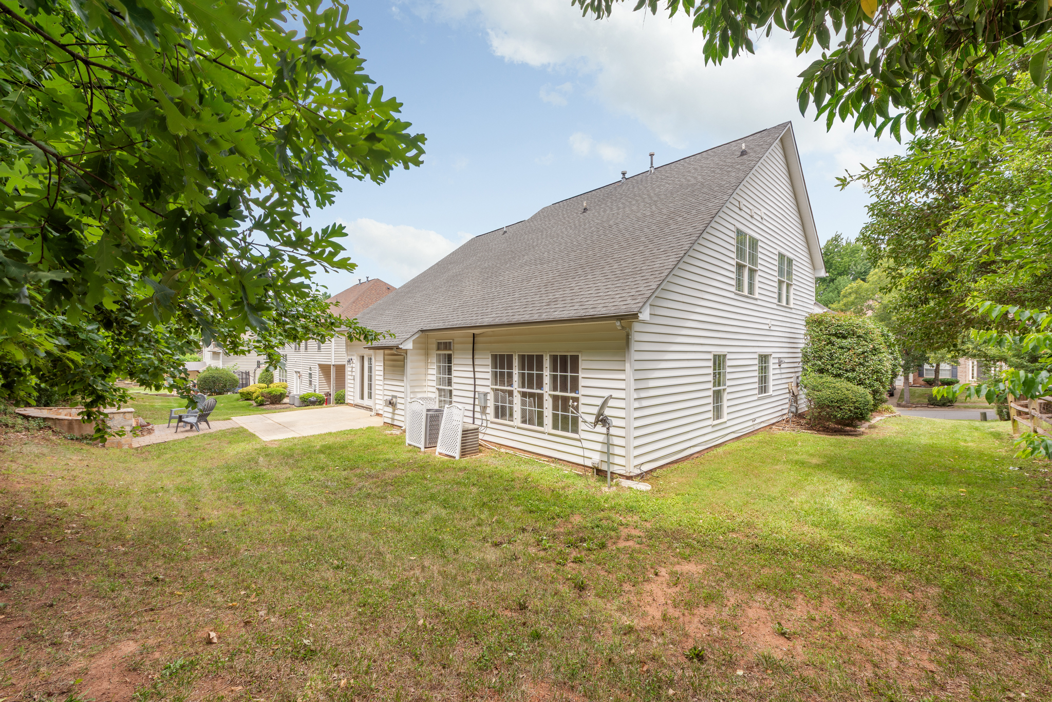 Rear exterior view showing white siding, gray roof, and stone retaining wall