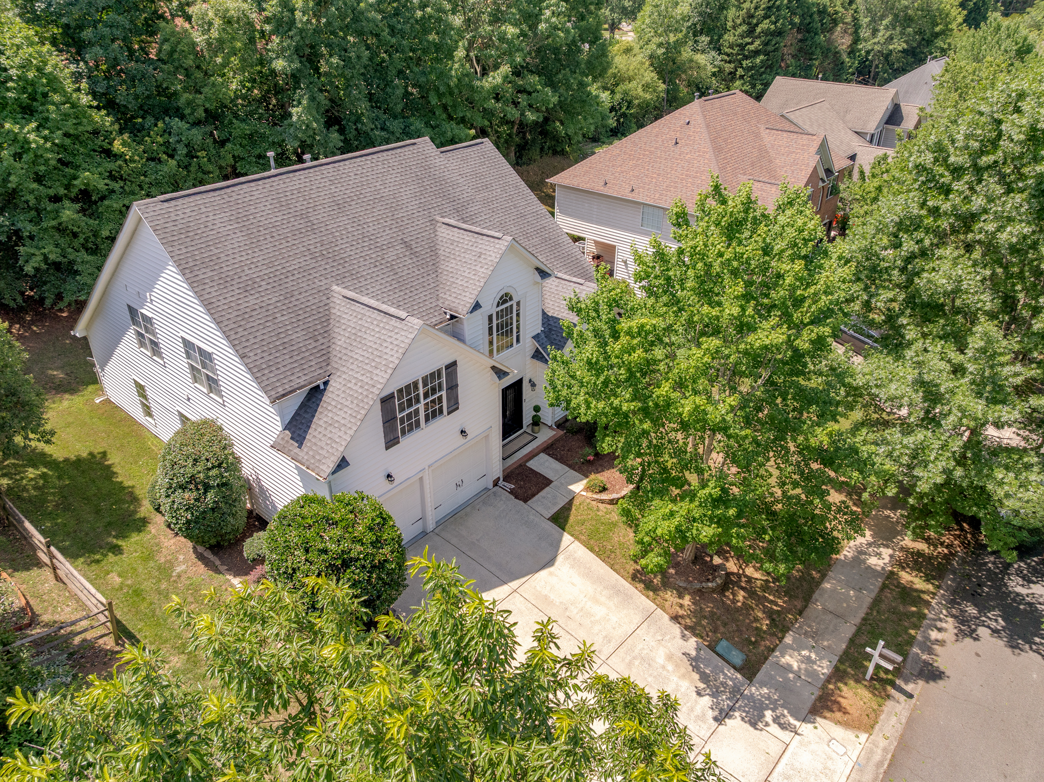 Drone aerial view of the property showing driveway, mature trees, and roofline