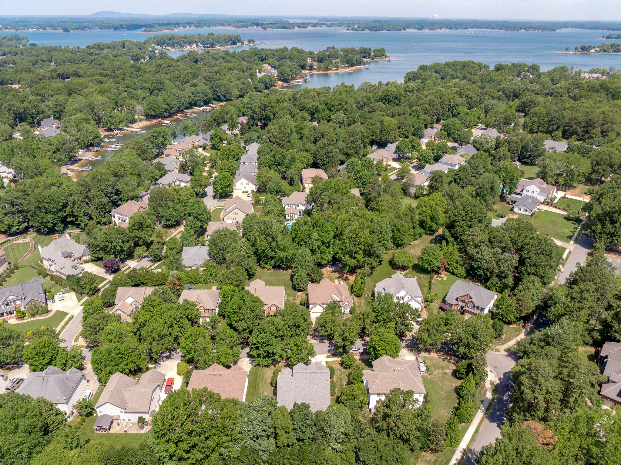 Drone aerial of residential neighborhood near Lake Norman with forest canopy and lake waters