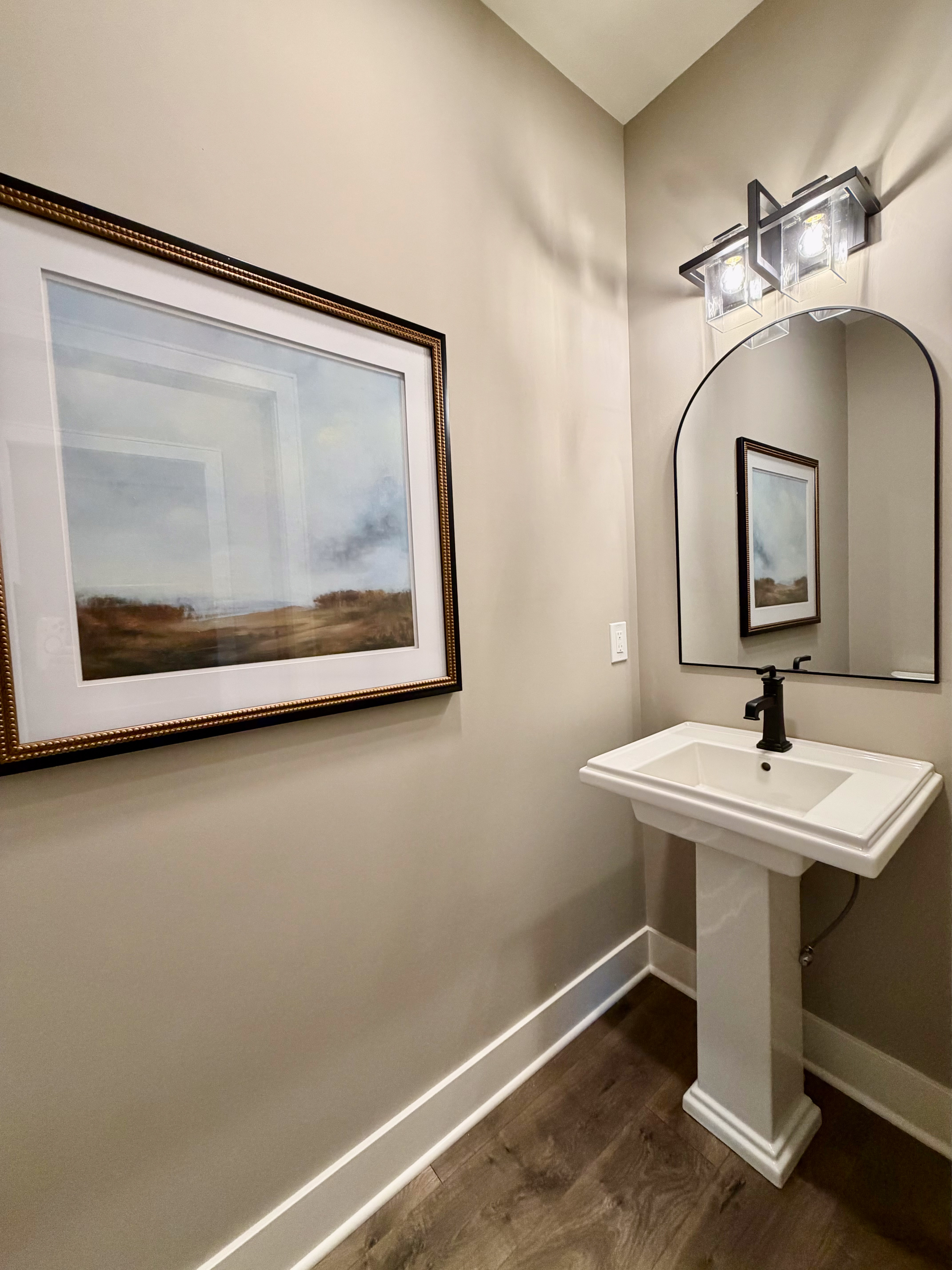Powder room with white pedestal sink and geometric vanity light