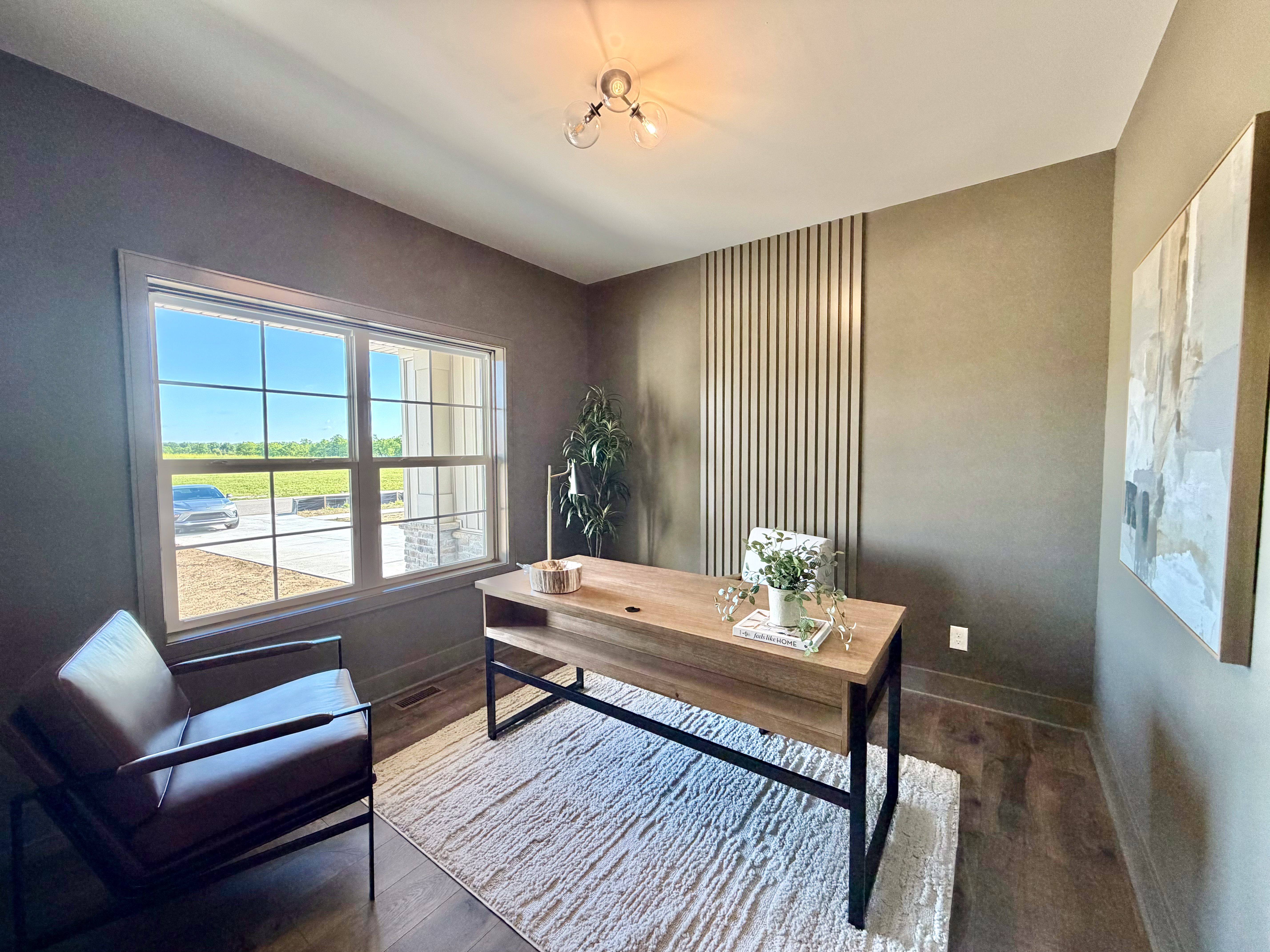 Home office with vertical slat wood accent wall and large grid-pane window