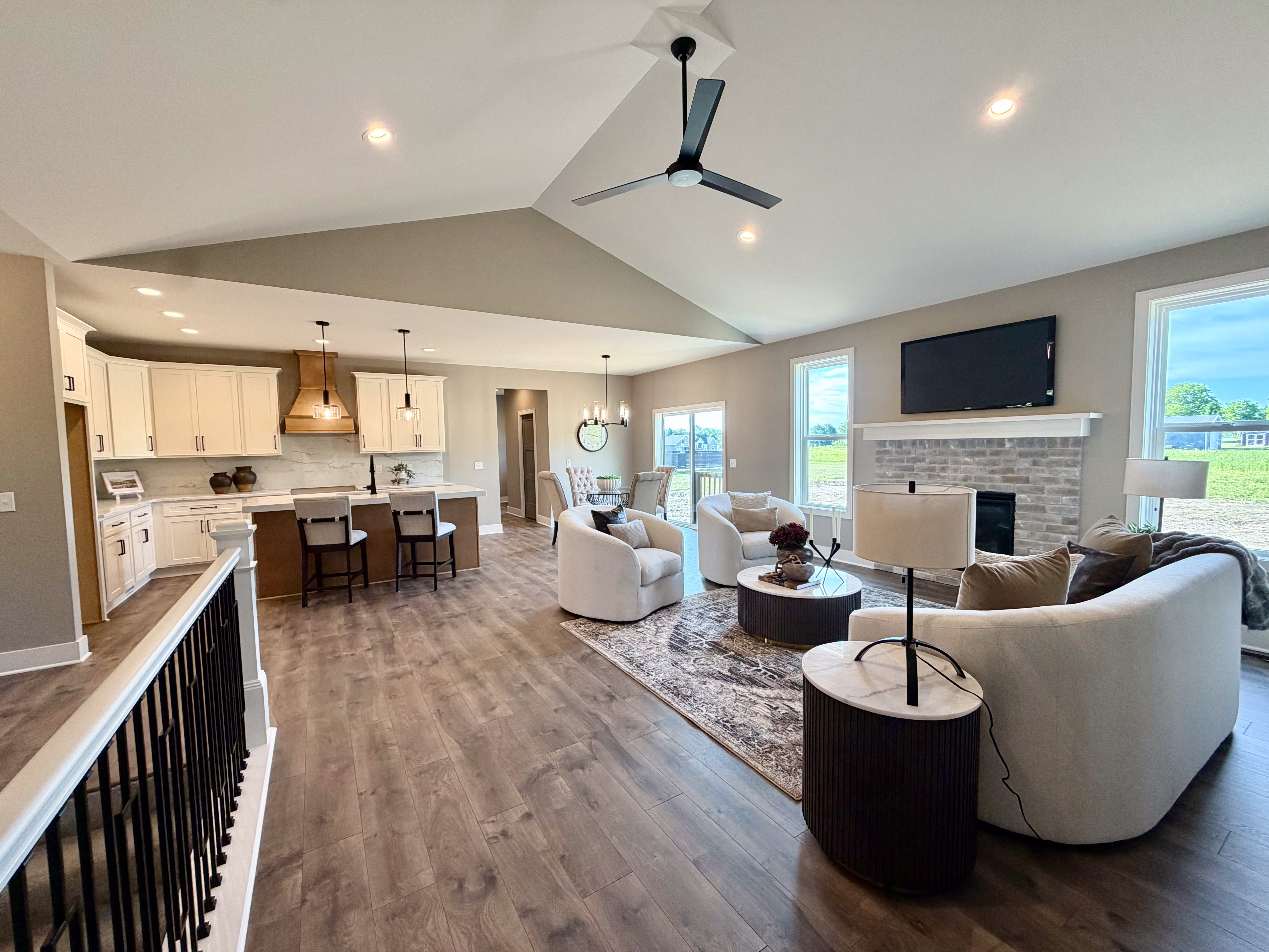 Open concept great room with vaulted ceilings, stone fireplace, and kitchen — Big Sky Development model home