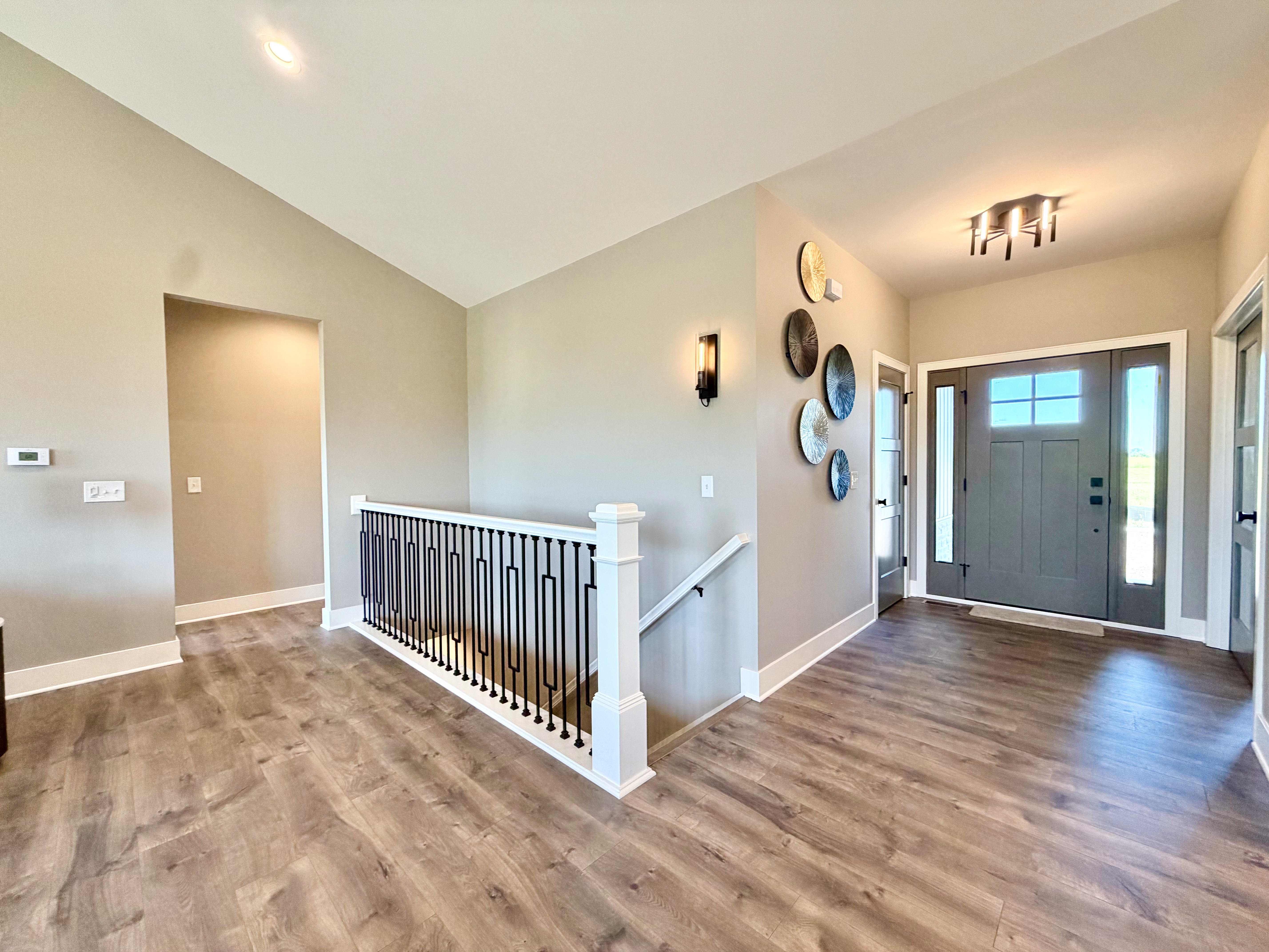 Foyer entryway with luxury vinyl plank flooring and matte black metal baluster staircase