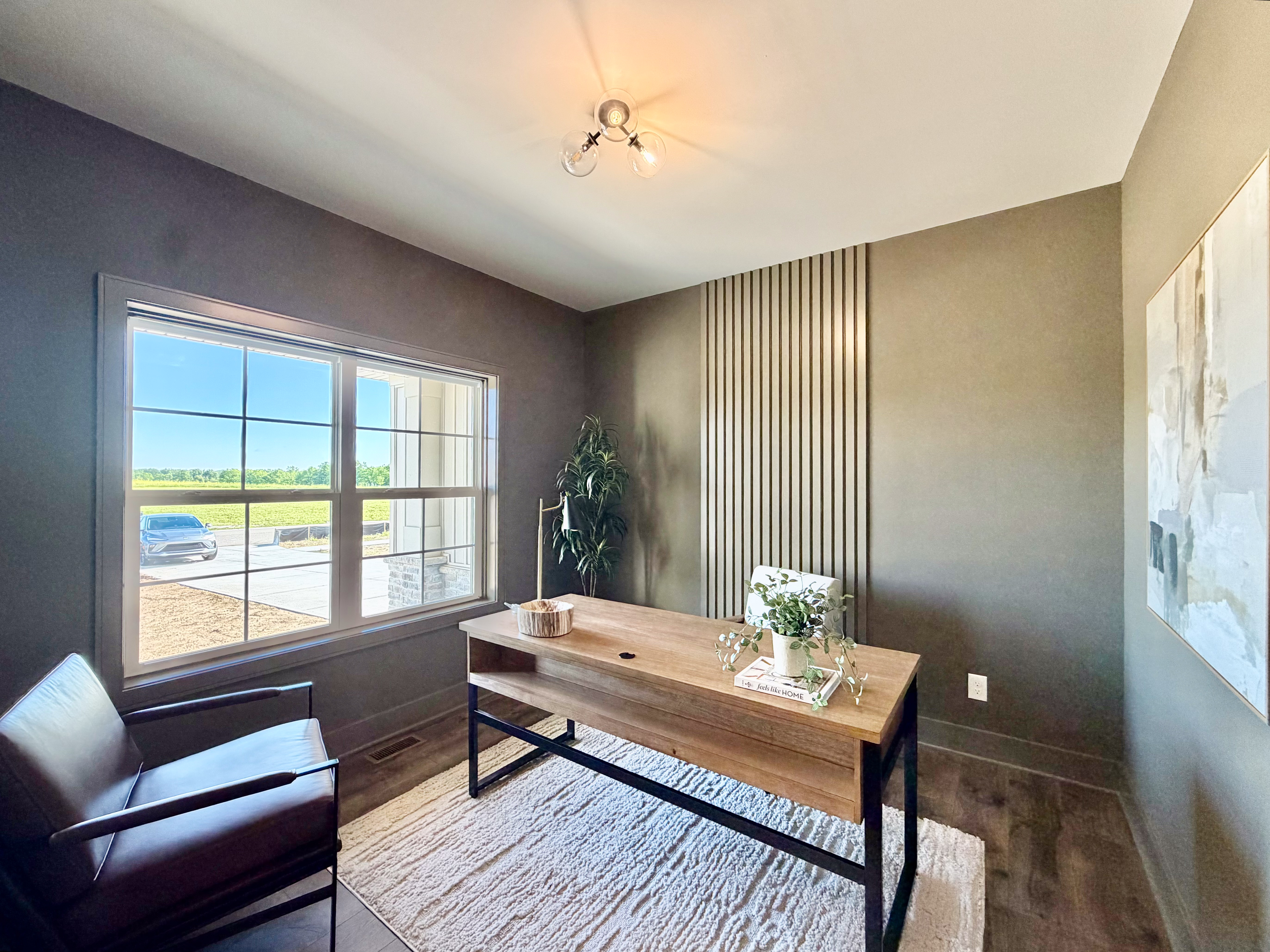 Study with dark paint, slat accent wall, and large window