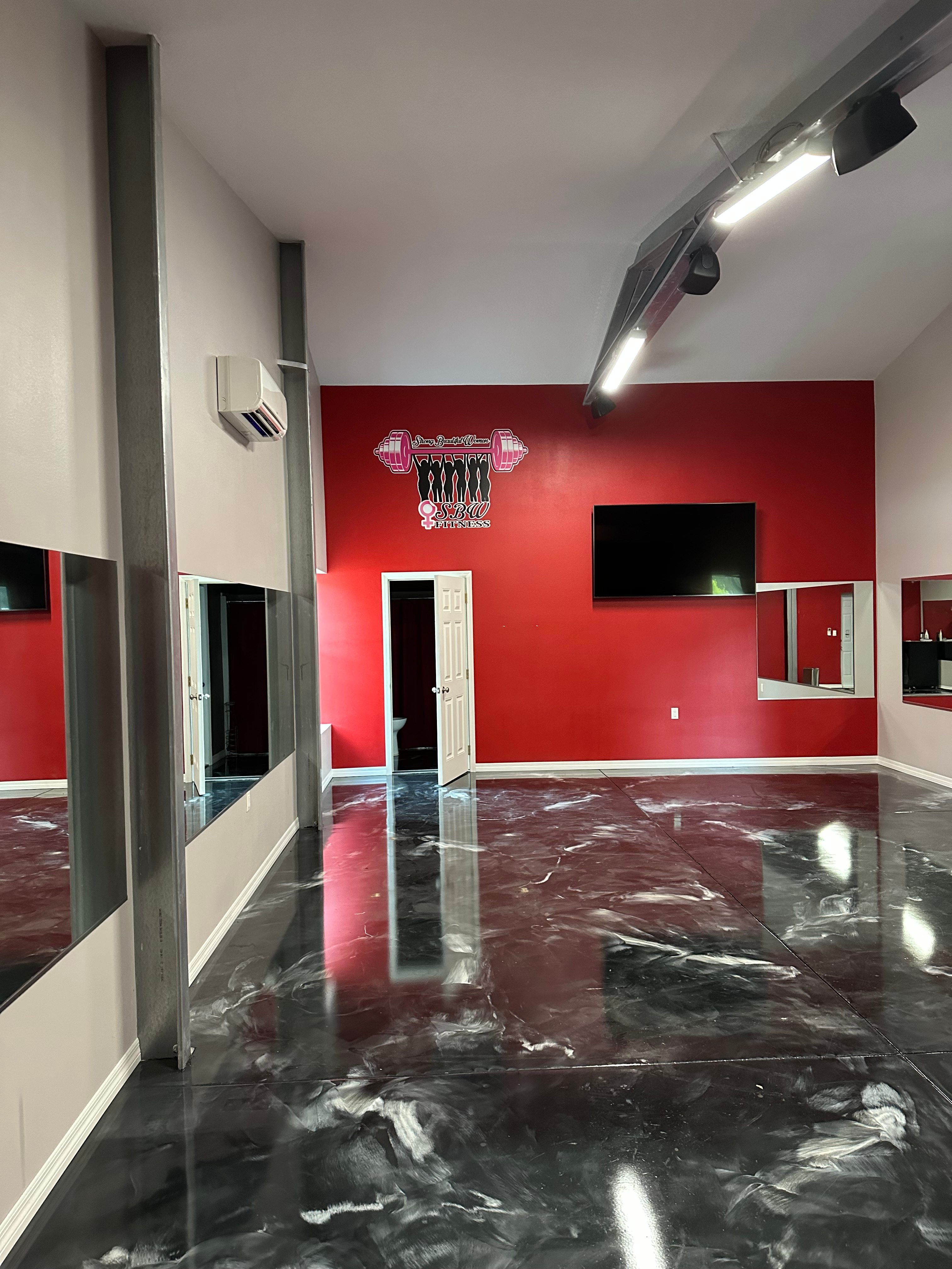 Gym studio in the flex building with dark epoxy floors and red accent walls