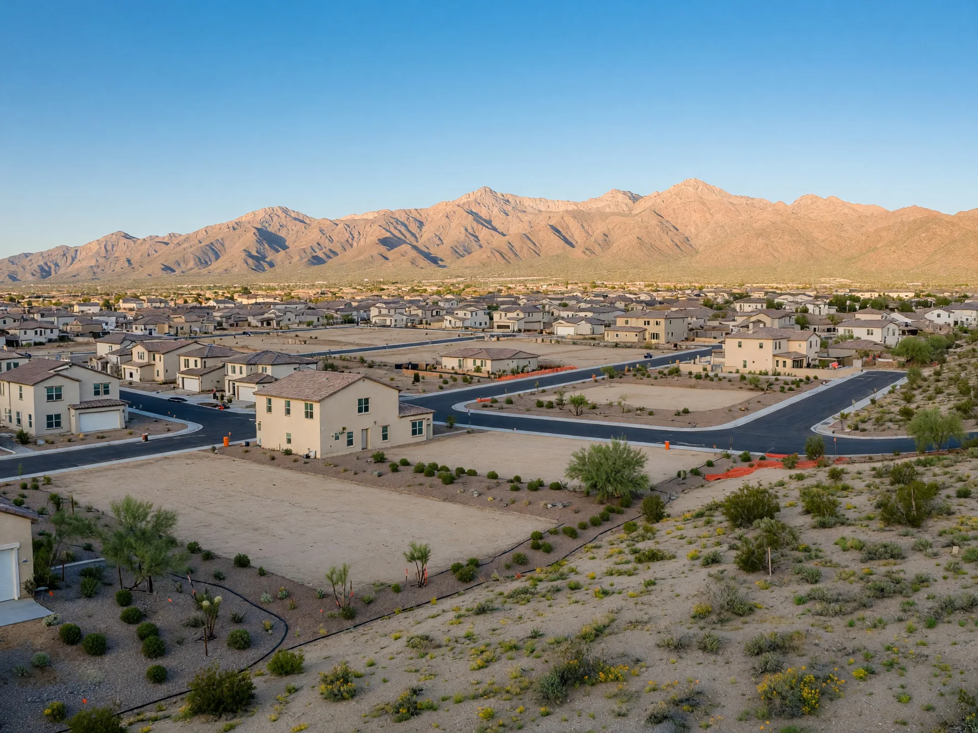 Newer large-scale development in Goodyear with wide desert lots, stucco homes, and the Estrella Mountains prominent in the background