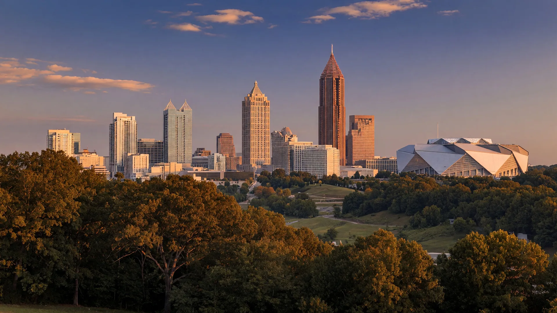 Atlanta skyline at golden hour with Bank of America Plaza and One Atlantic Center visible above the tree canopy