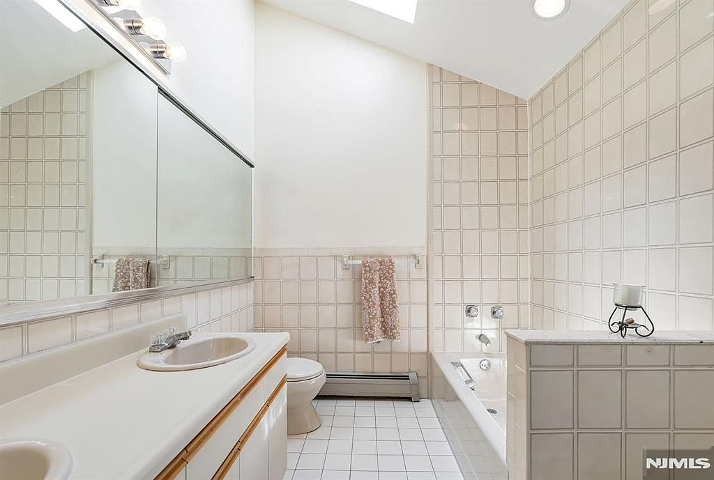 Primary bathroom with skylight, jacuzzi tub, and beige tile