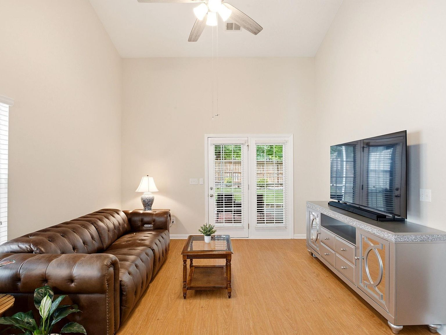 Vaulted great room with laminate flooring and French doors leading to the screened porch