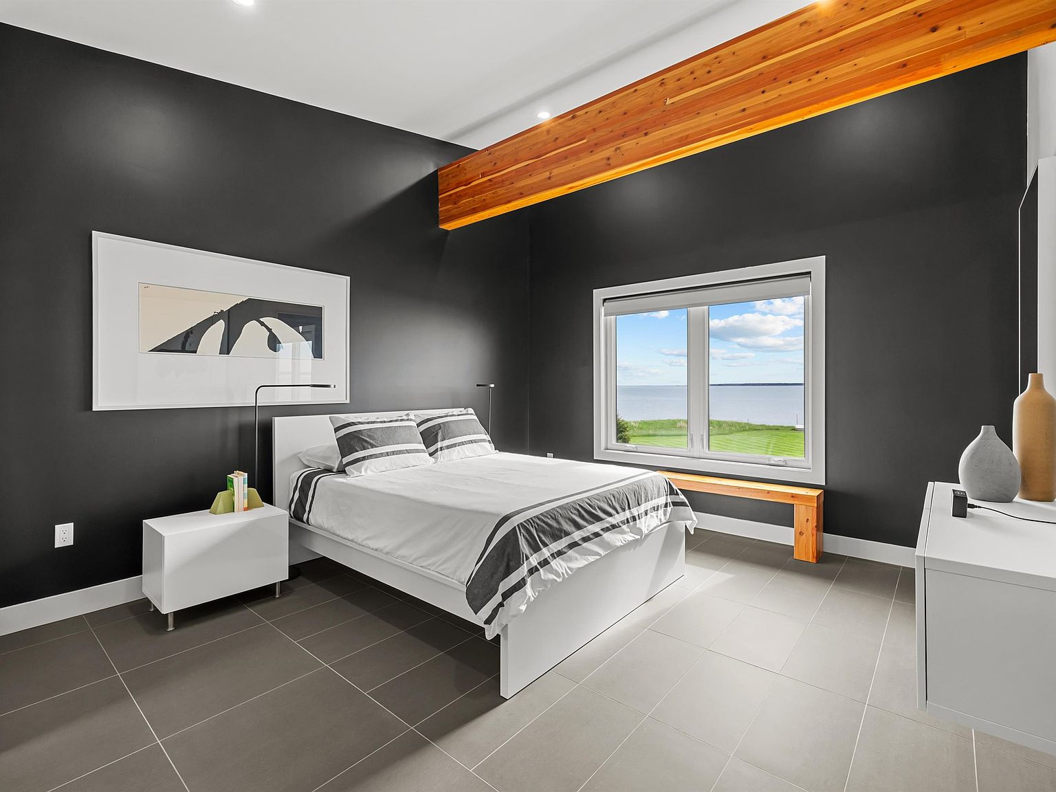 Primary bedroom with exposed timber beam and water view