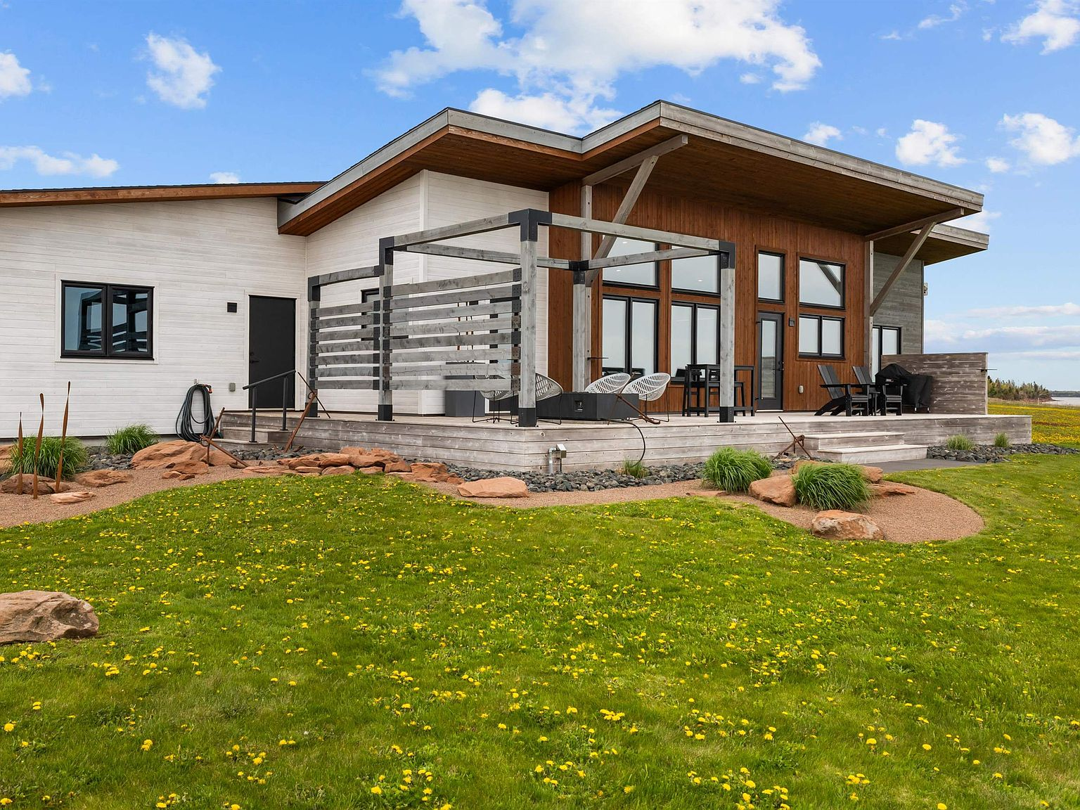 Rear facade with pergola, deck, and landscaping