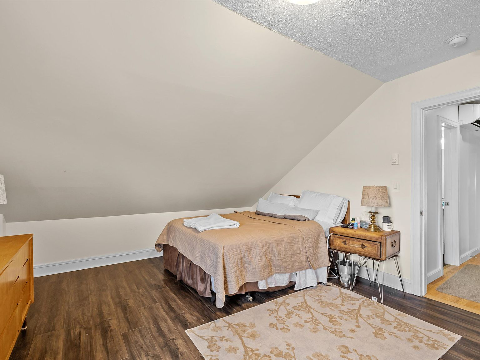 Attic bedroom with sloped ceiling and dark wood-look flooring