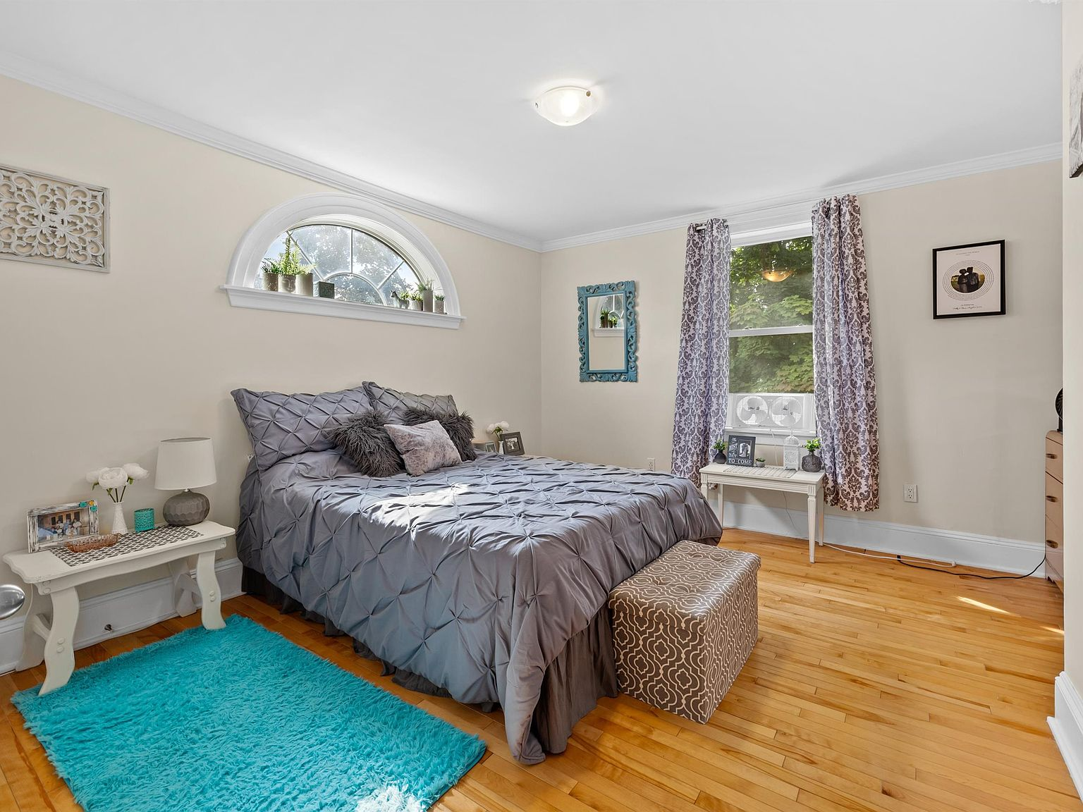 Master bedroom with arched window and hardwood floors