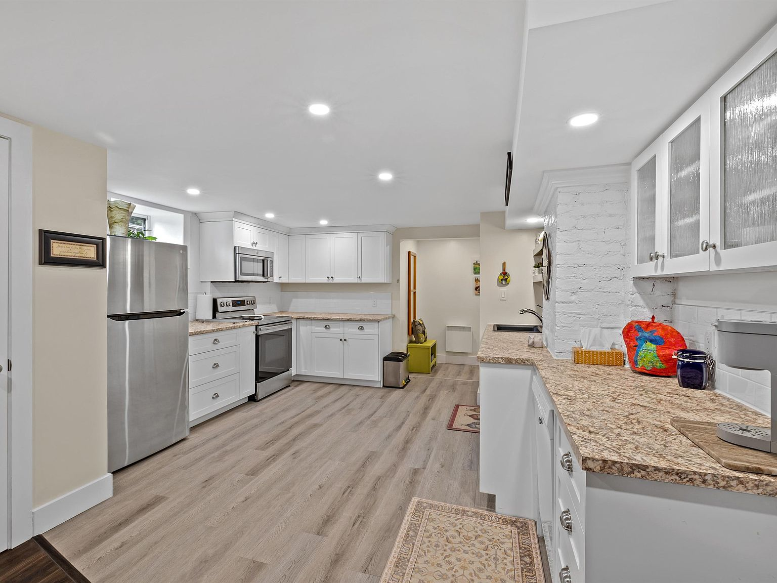 Renovated white kitchen with granite-look countertops and exposed brick