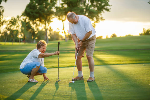 Older couple enjoying golf on a putting green at golden hour in The Villages, Florida