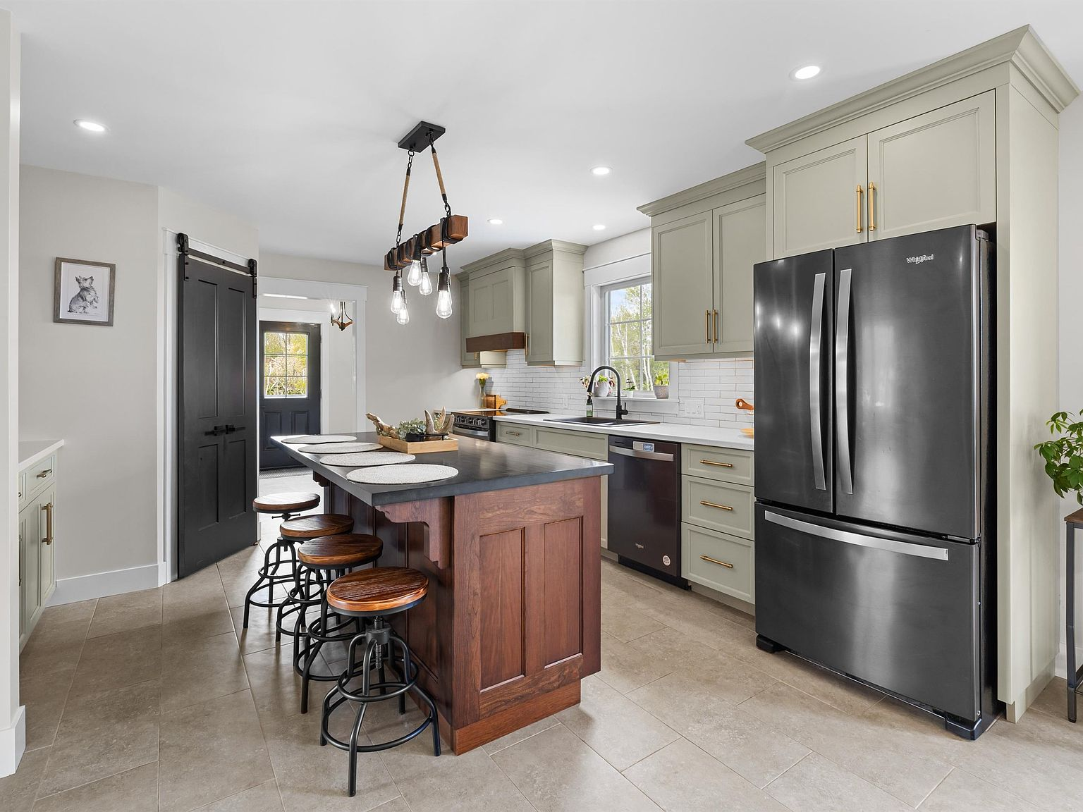 Chef's kitchen with sage green cabinetry, dark granite countertops, and wood-stained island