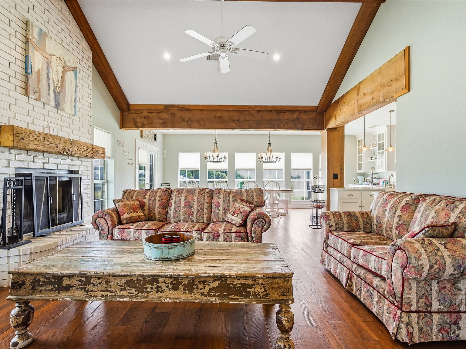 43-foot living room with vaulted ceilings, exposed wooden beams, and white brick fireplace