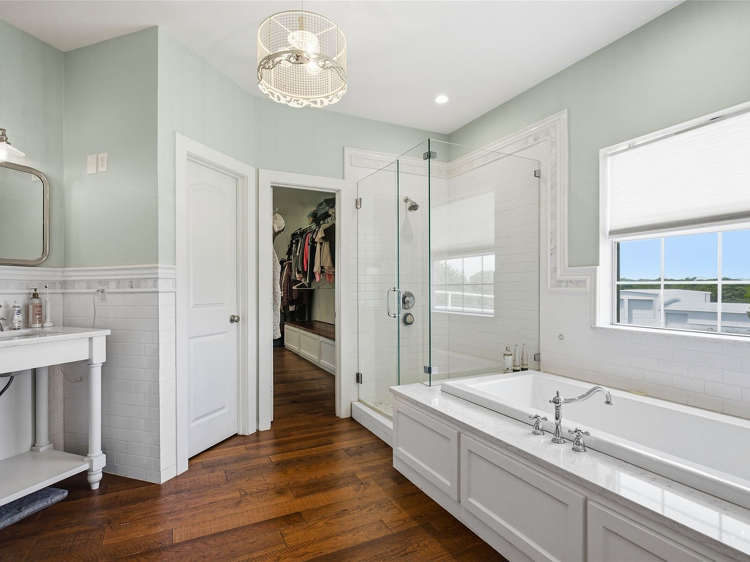 Primary bathroom with white cabinetry, glass shower, and soaking tub