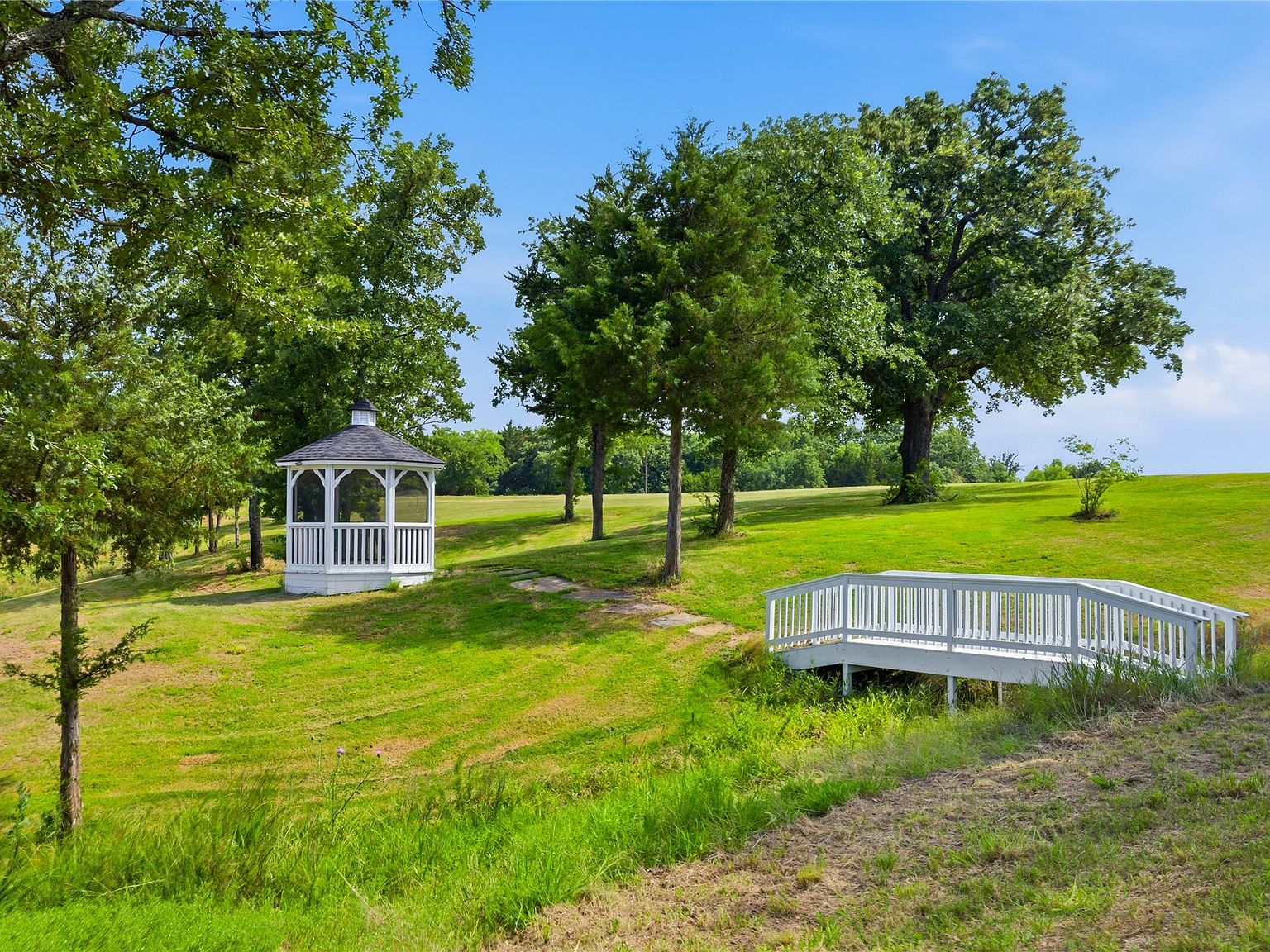 White wooden gazebo and matching pedestrian bridge on the estate grounds