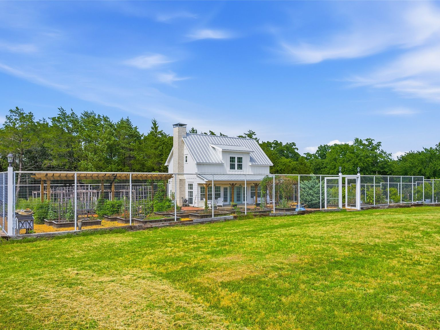 Two-story guest cottage with fenced vegetable garden and raised beds
