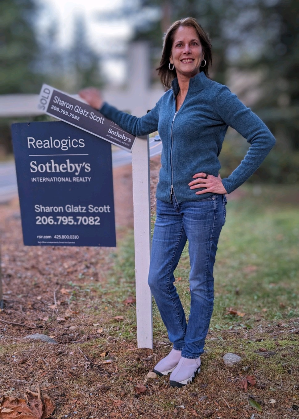 Sharon Glatz Scott standing beside a Realogics Sotheby's International Realty sold sign