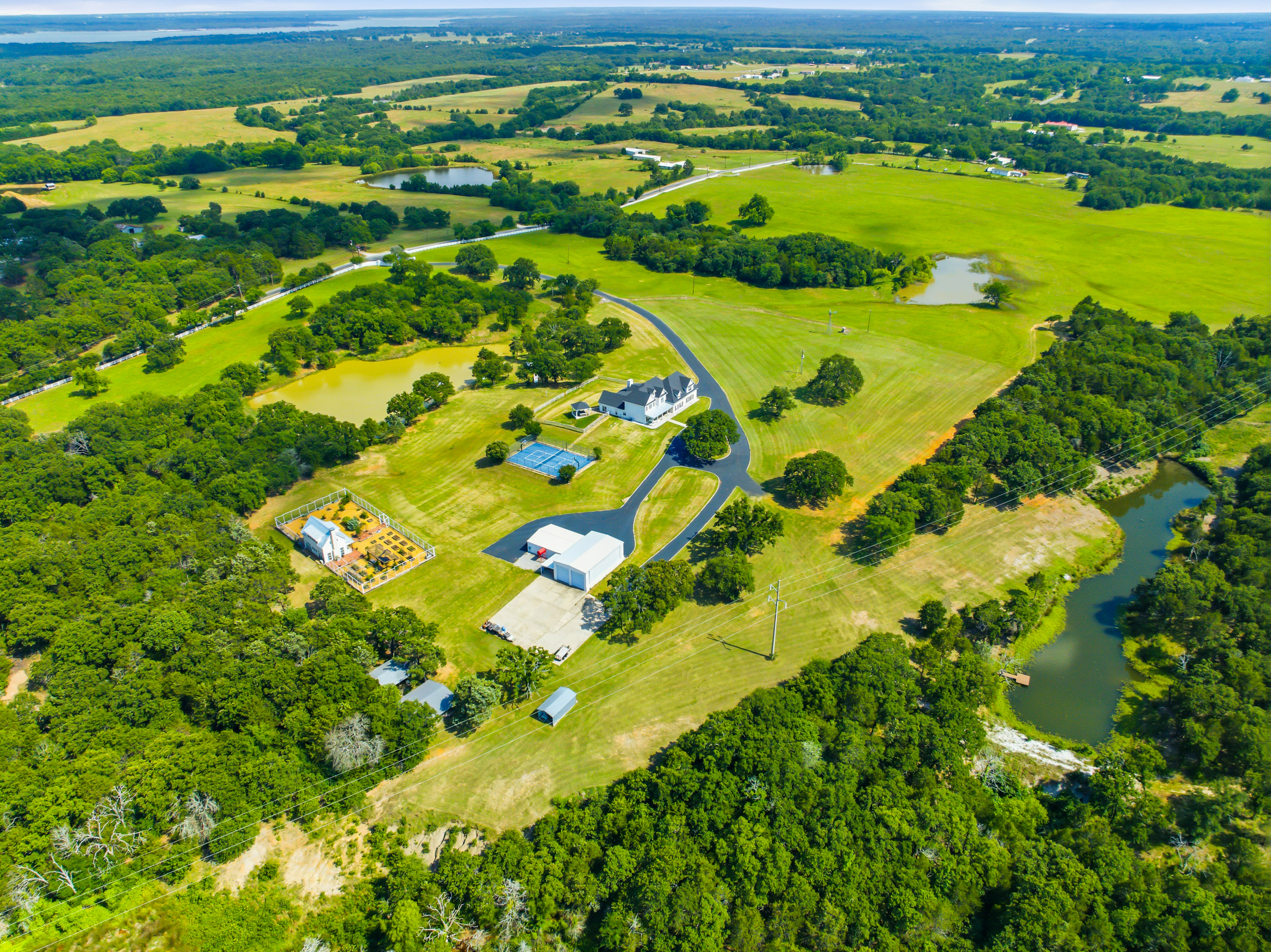 Aerial view of a 50-acre estate with rolling green hills and Lake Texoma in the distance