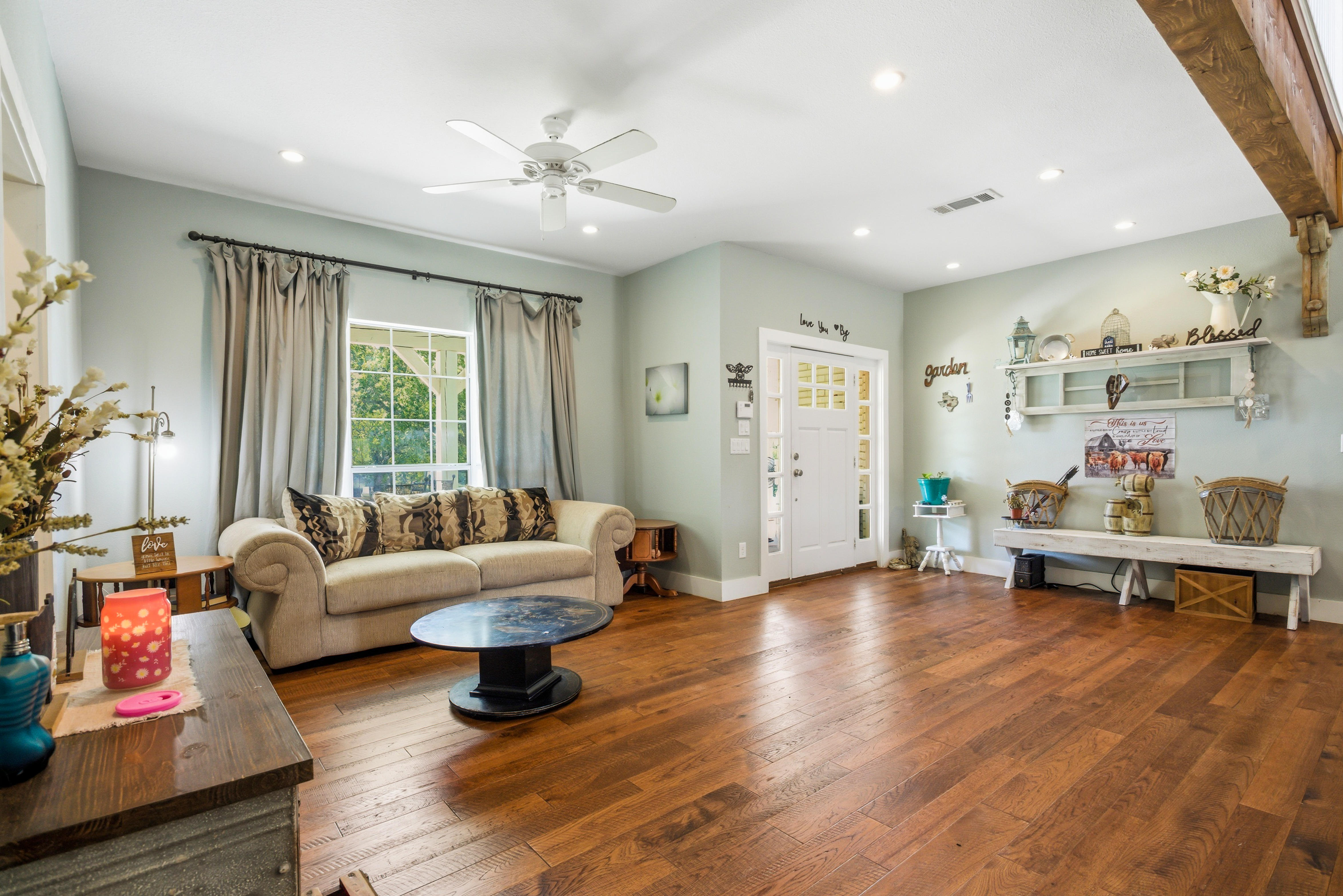 Living room with exposed wood beam detail, hardwood floors, and natural light
