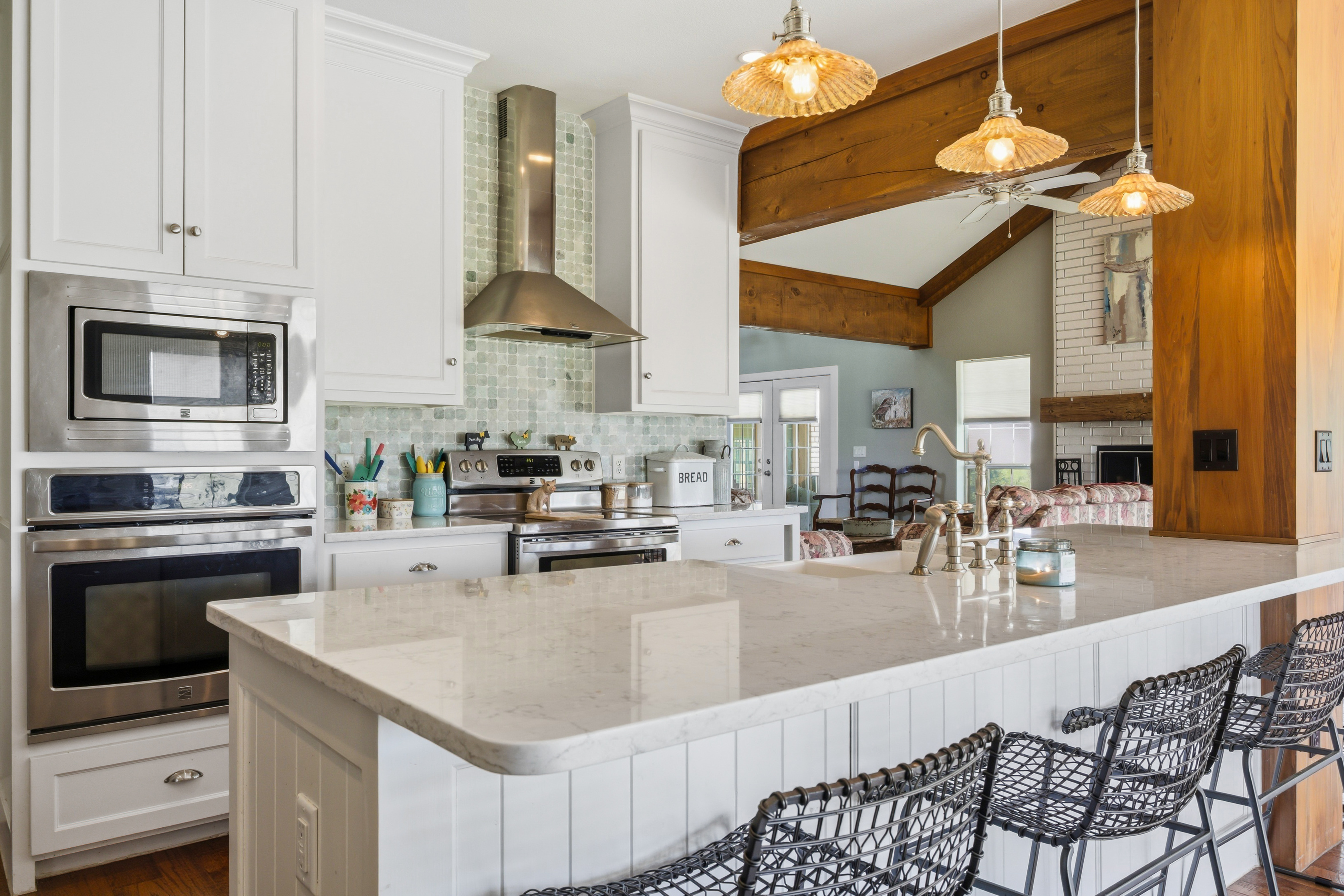 Kitchen perspective toward living room with wood beams and architectural support posts