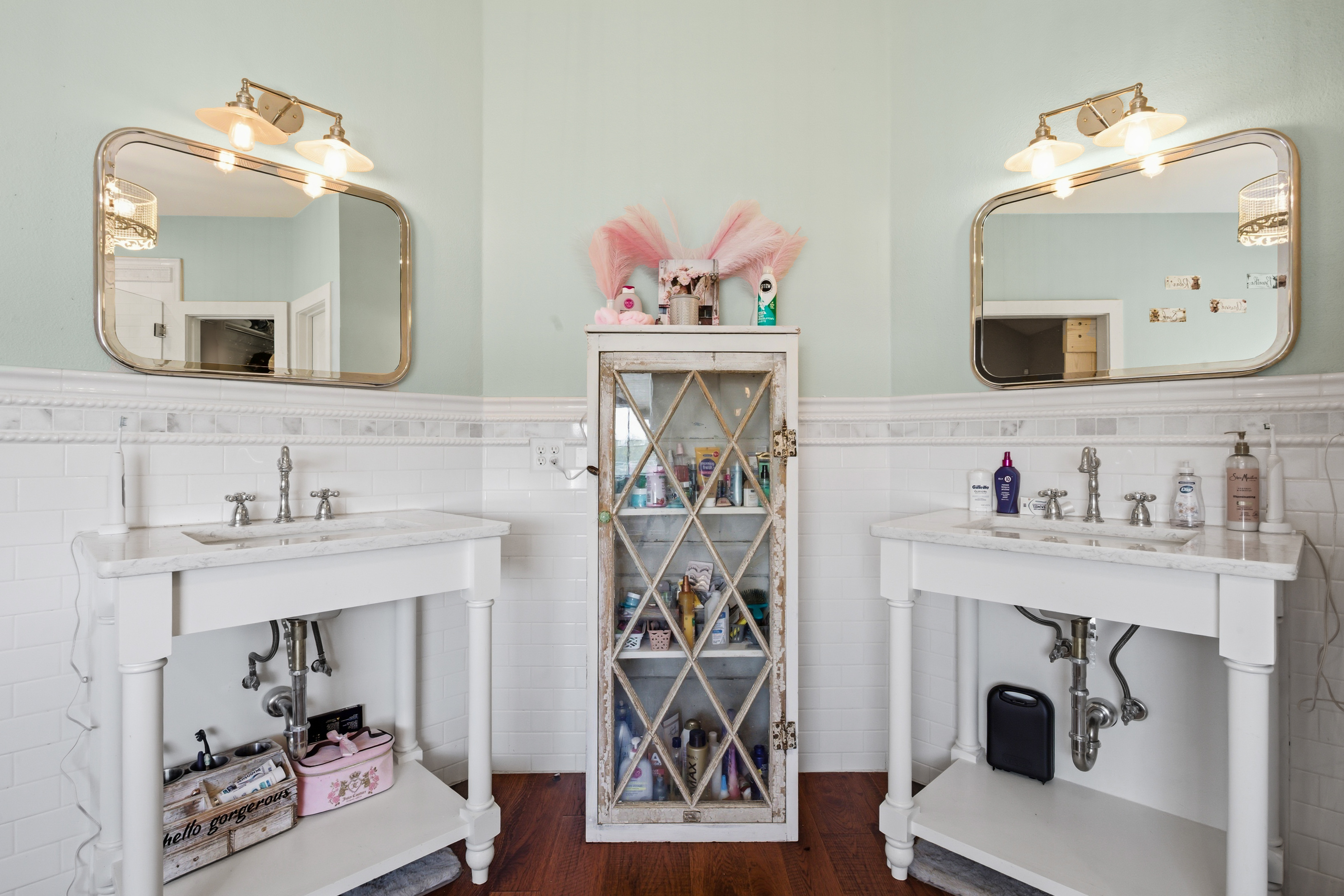 Dual vanity with white subway tile, brass-framed mirrors, and mint green walls
