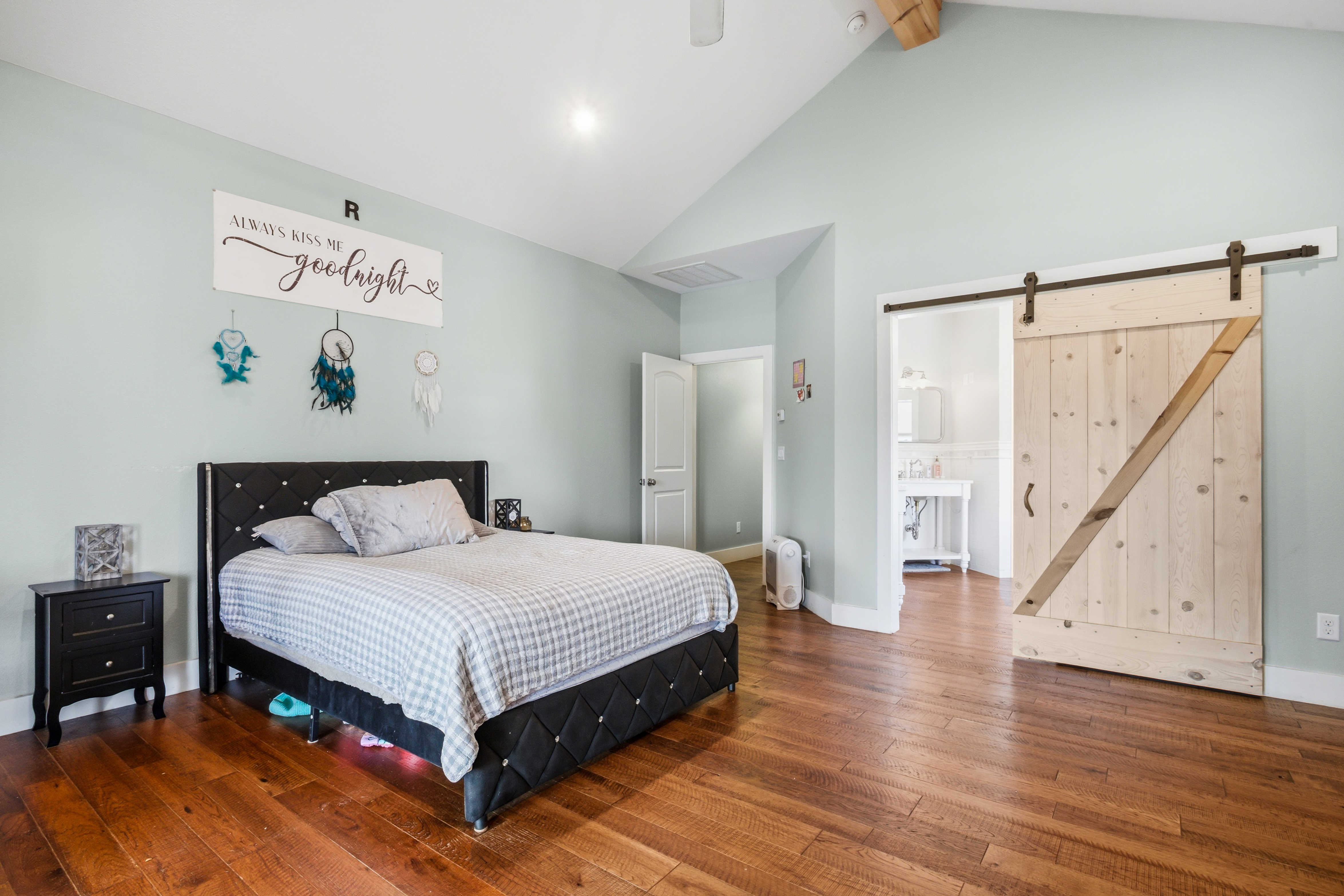 Bedroom with aqua walls, vaulted ceiling, and sliding barn door