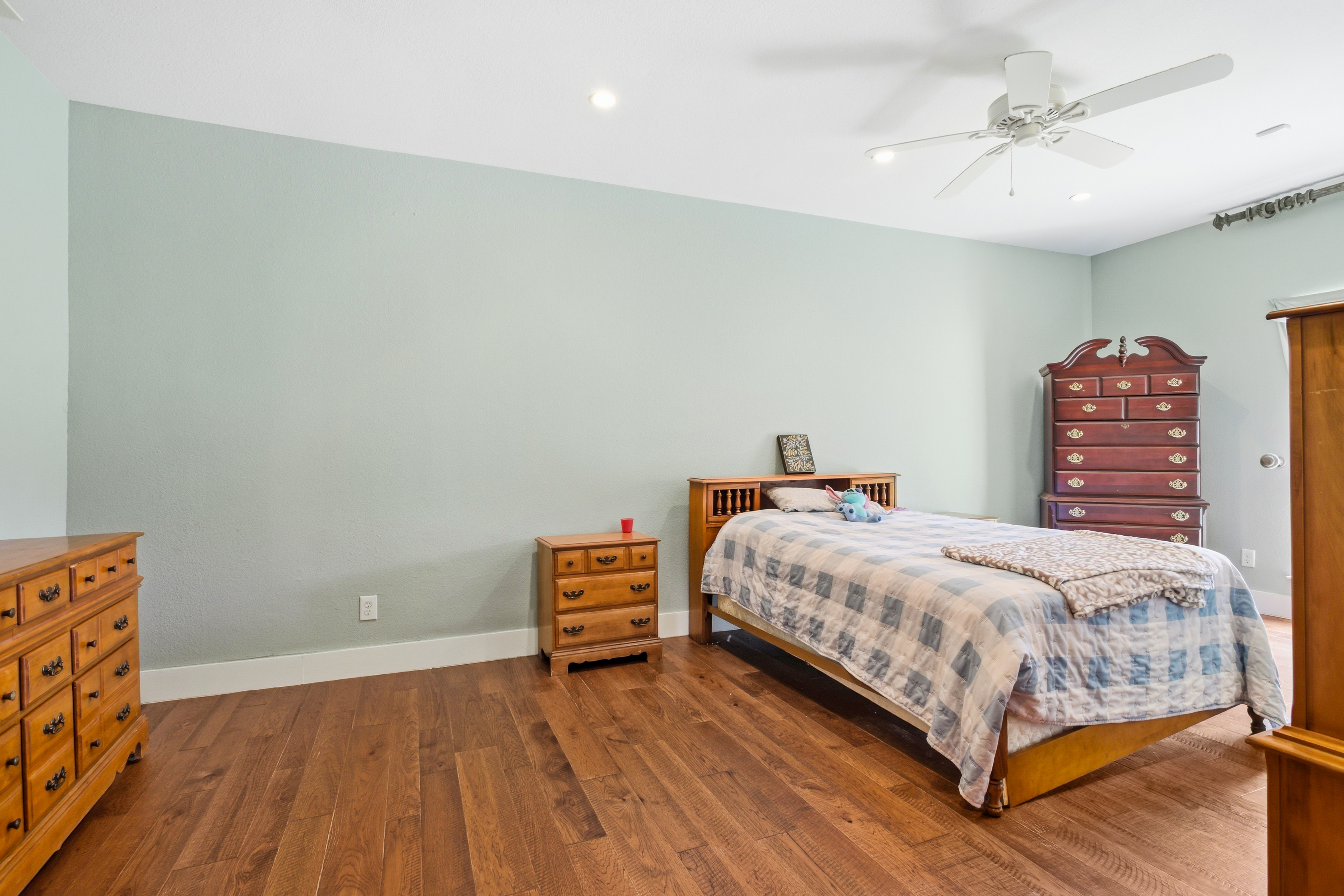 Secondary bedroom with light green walls and dark wood flooring