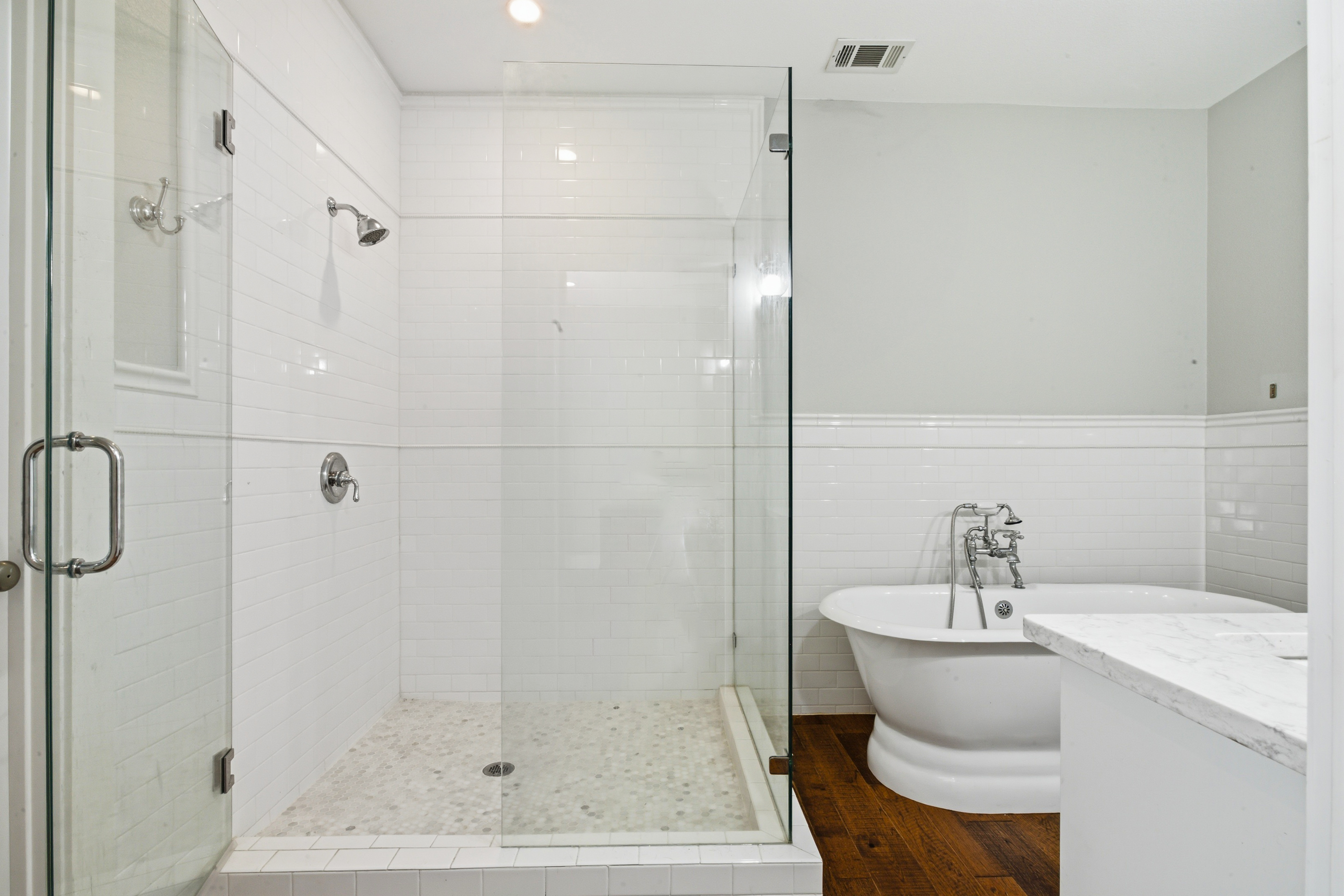 Master bathroom with subway tile shower, pebble floor, and freestanding tub