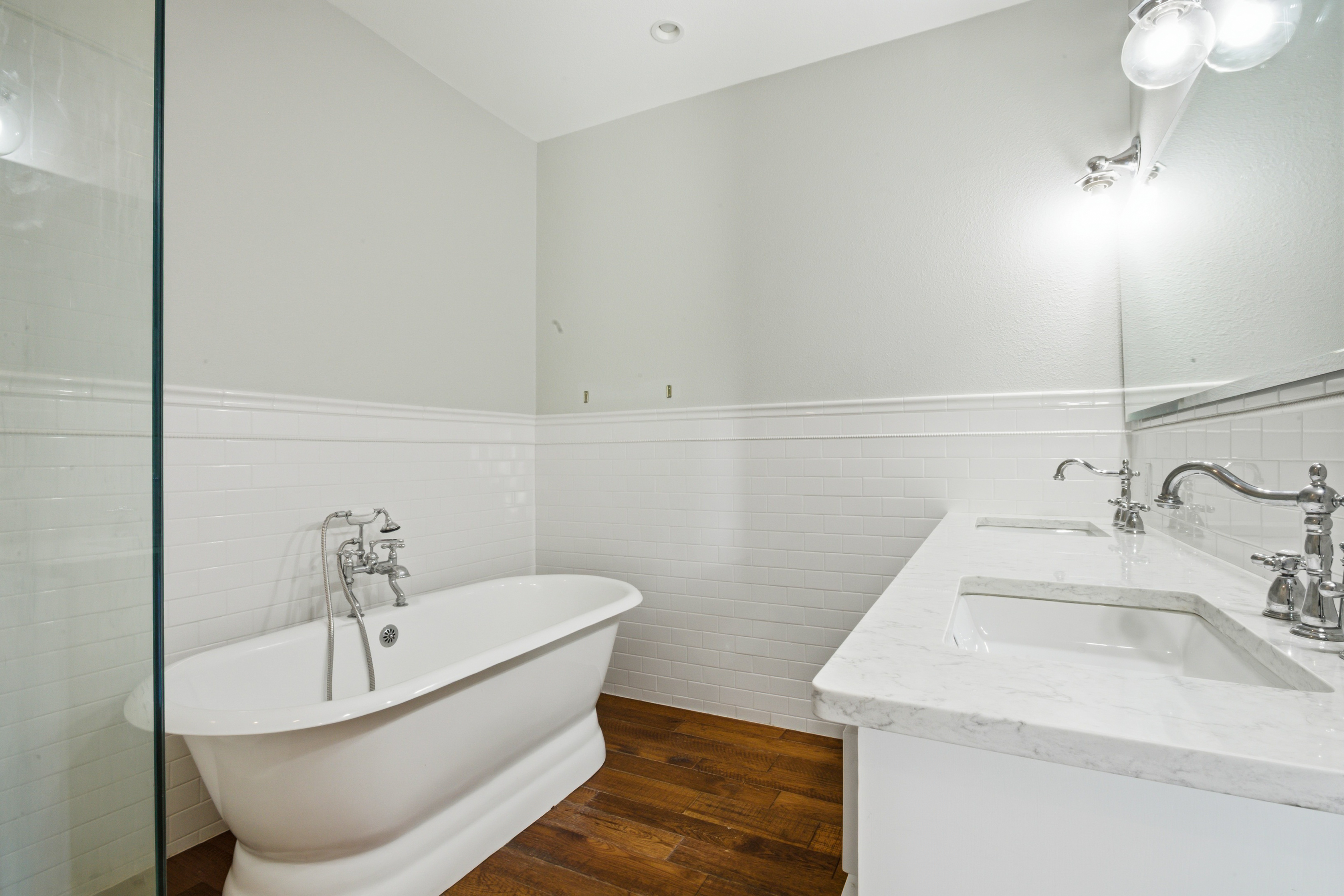 Master bath with freestanding soaking tub, quartz double vanity, and glass shower