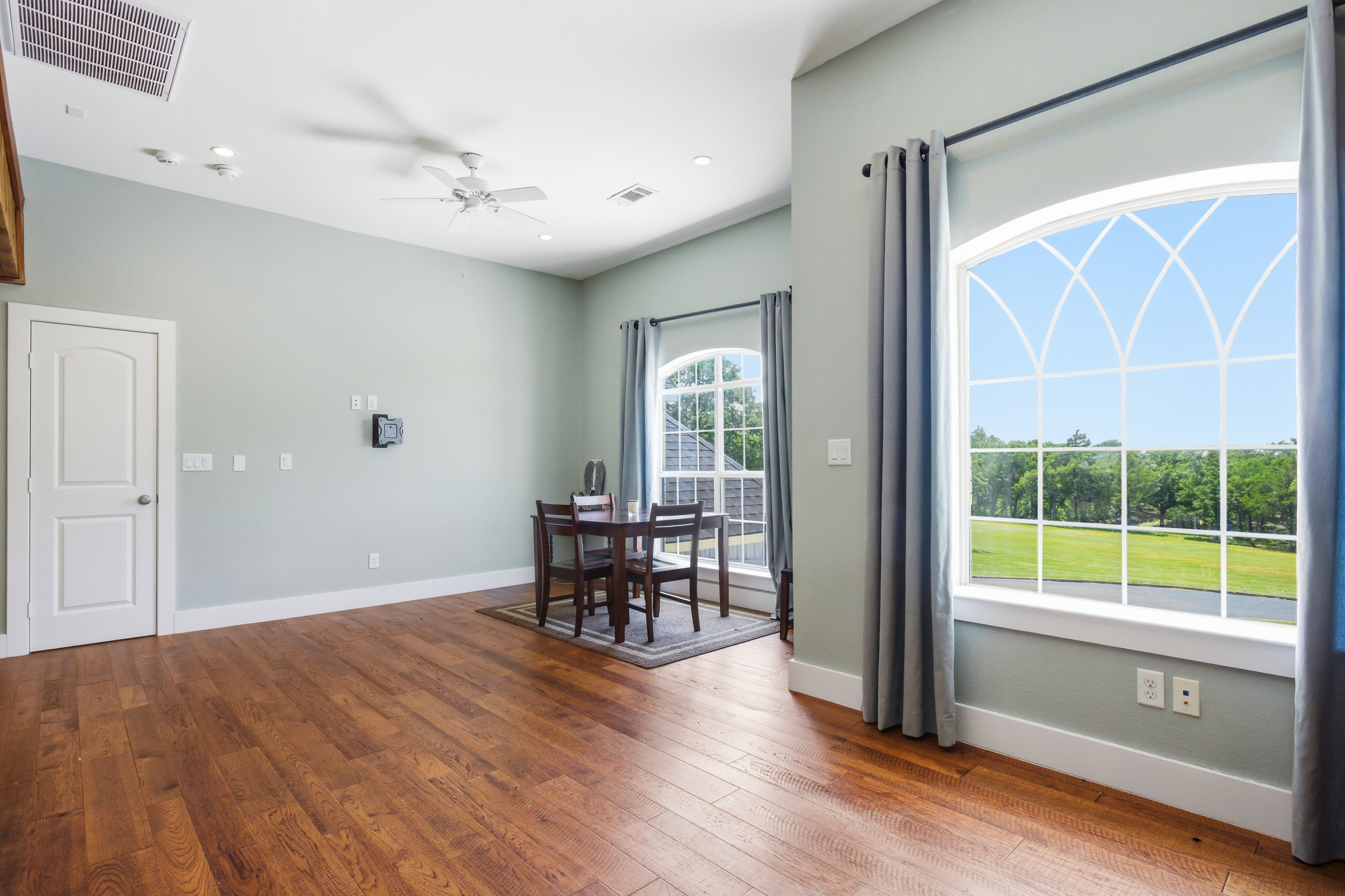 Bedroom with arched mullioned windows and warm hardwood floors