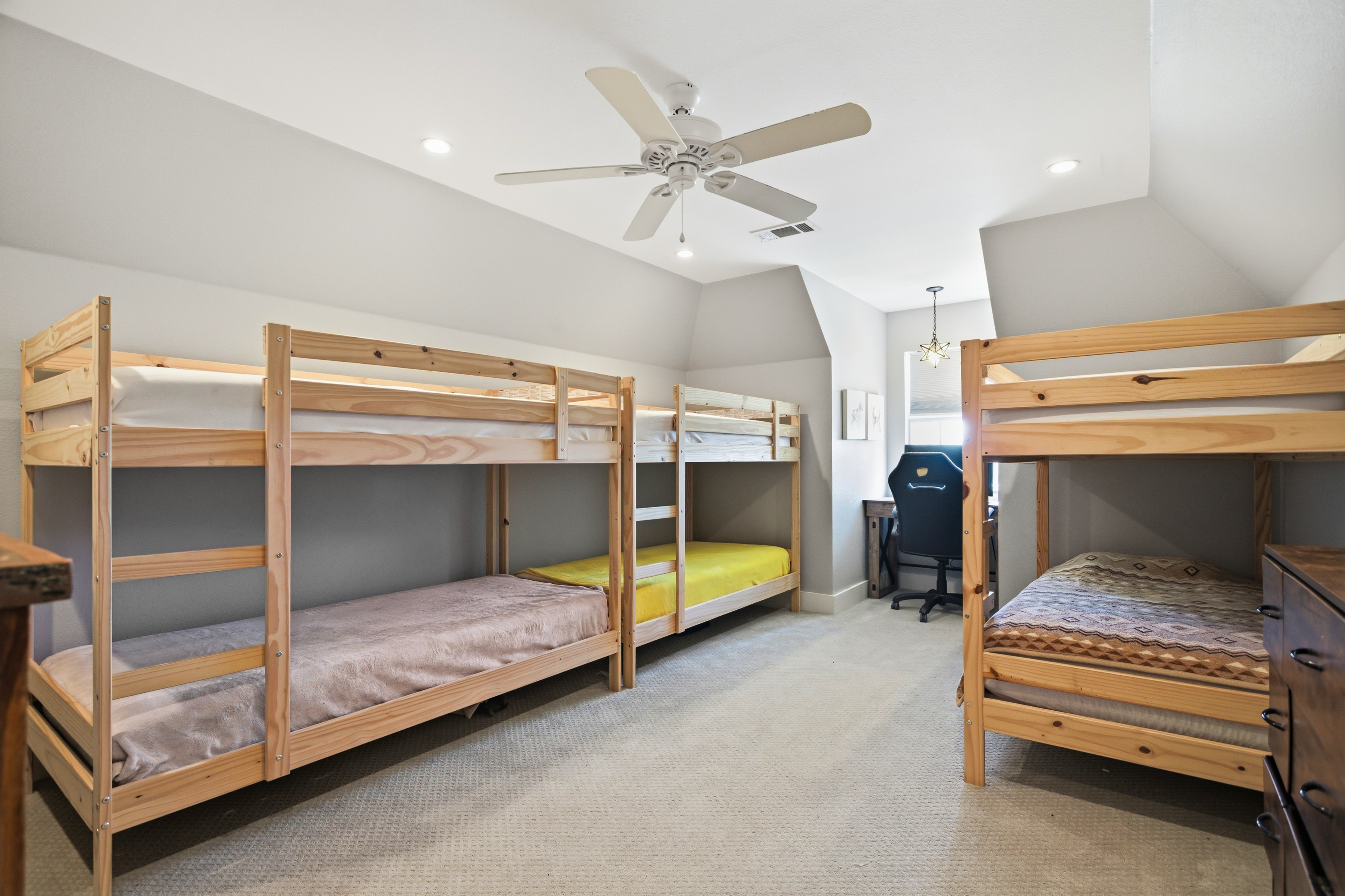 Upstairs bunk room with vaulted ceilings and carpet flooring