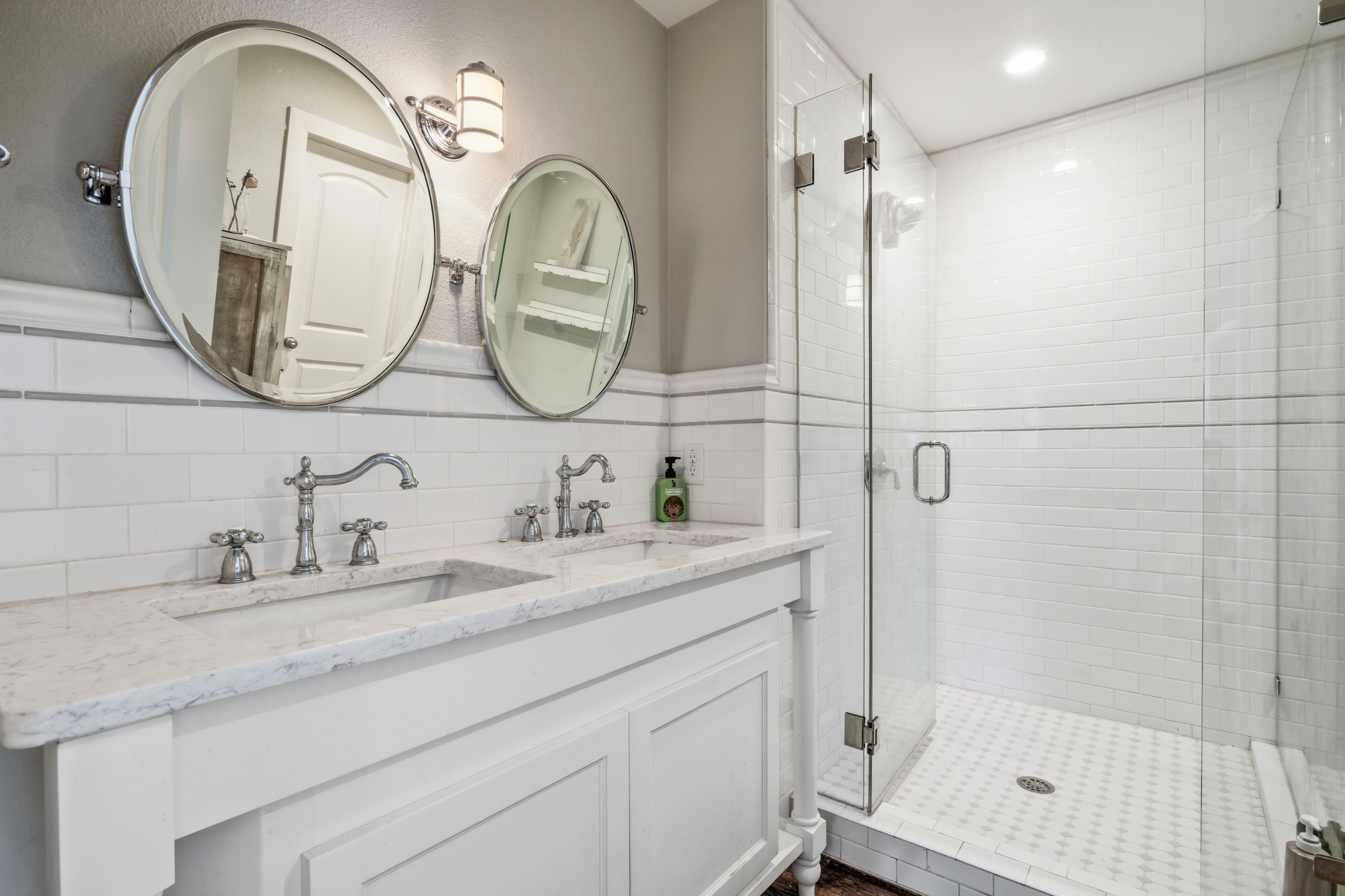 Bathroom with double vanity, subway tile, and chrome fixtures