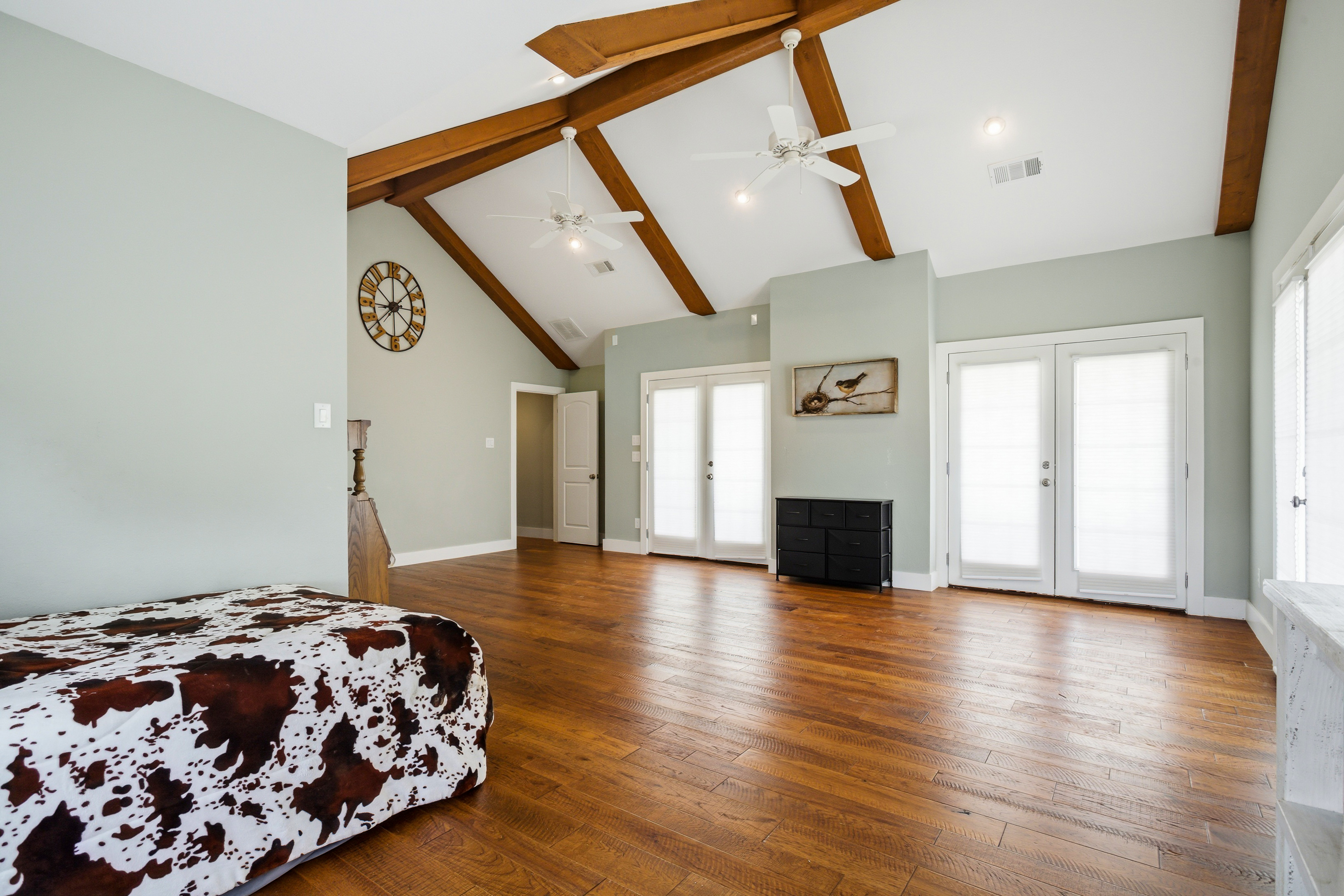 Vaulted bedroom suite with multiple glass patio doors and natural light