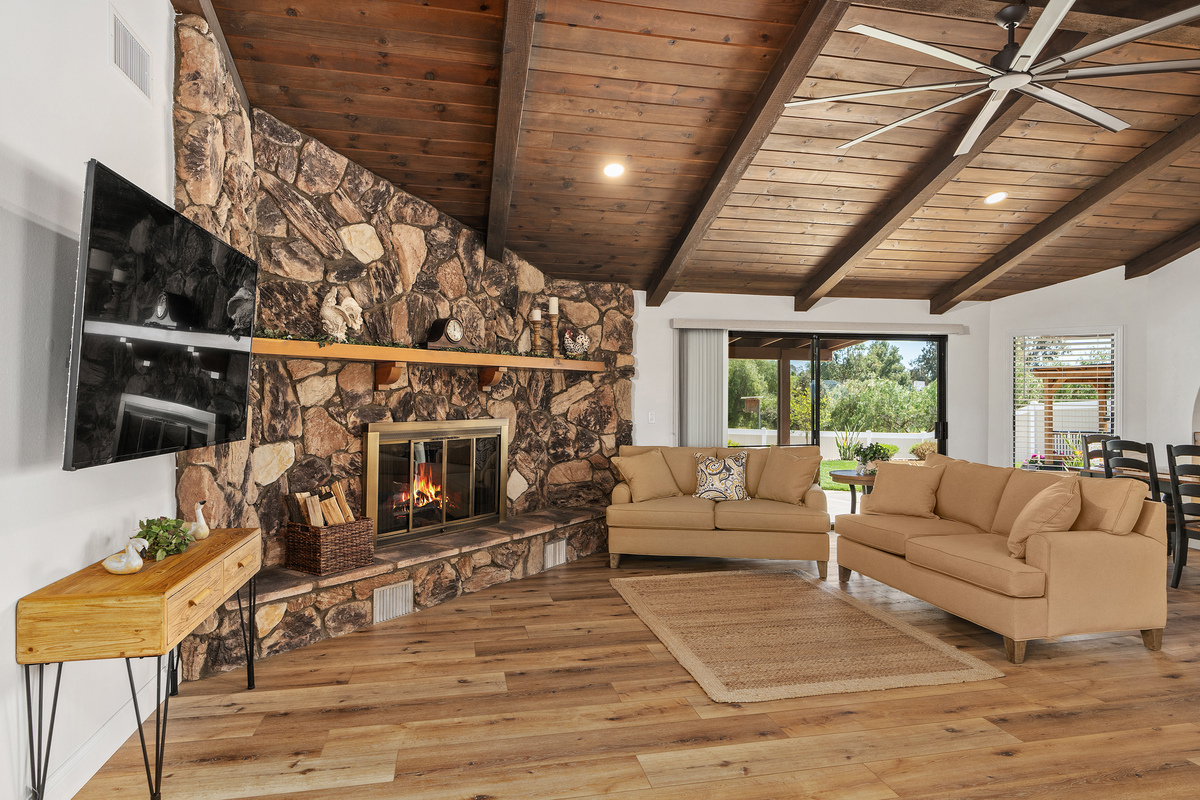 Living room with dramatic floor-to-ceiling stone fireplace and vaulted wood beam ceiling