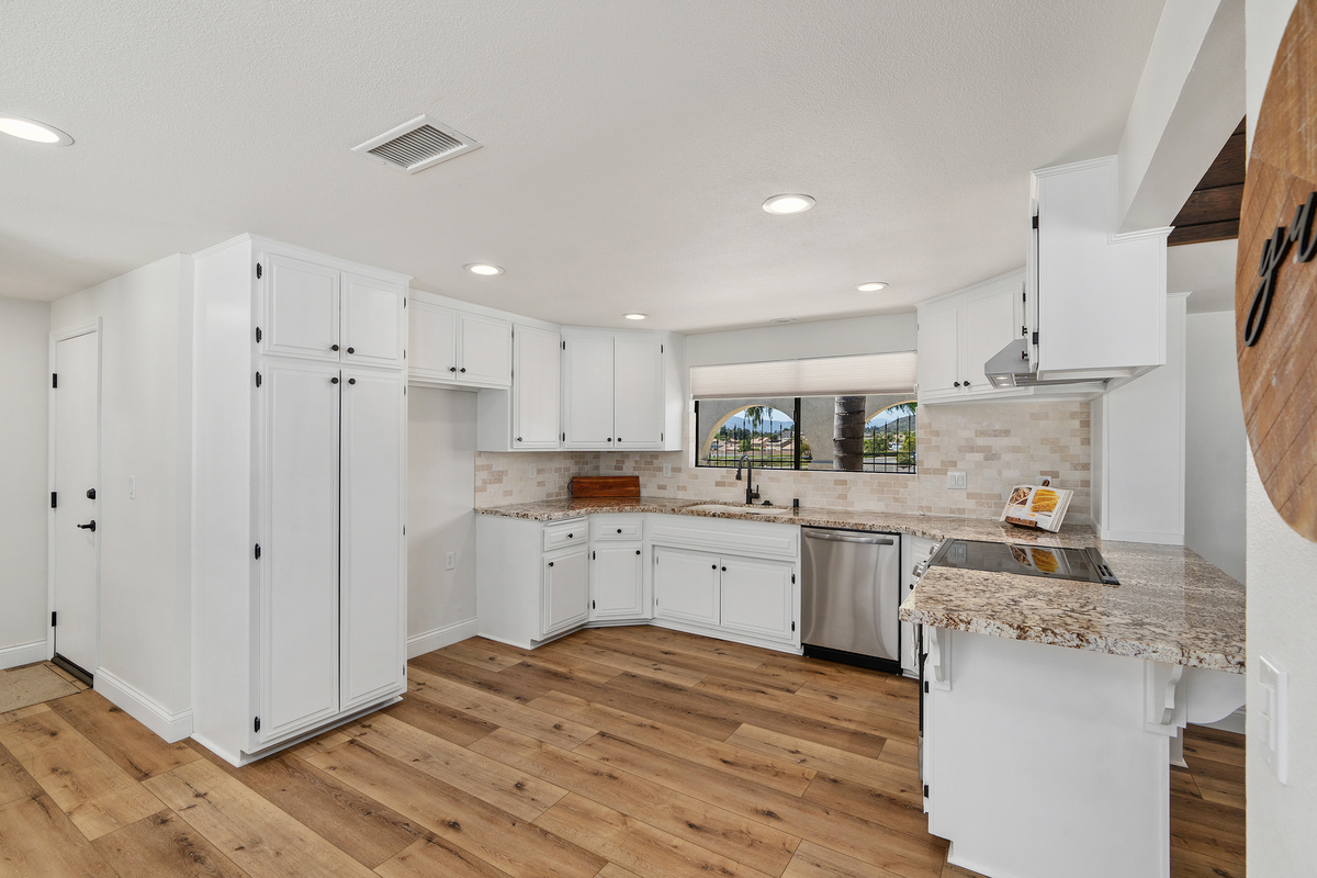 White kitchen with granite countertops and light brick backsplash