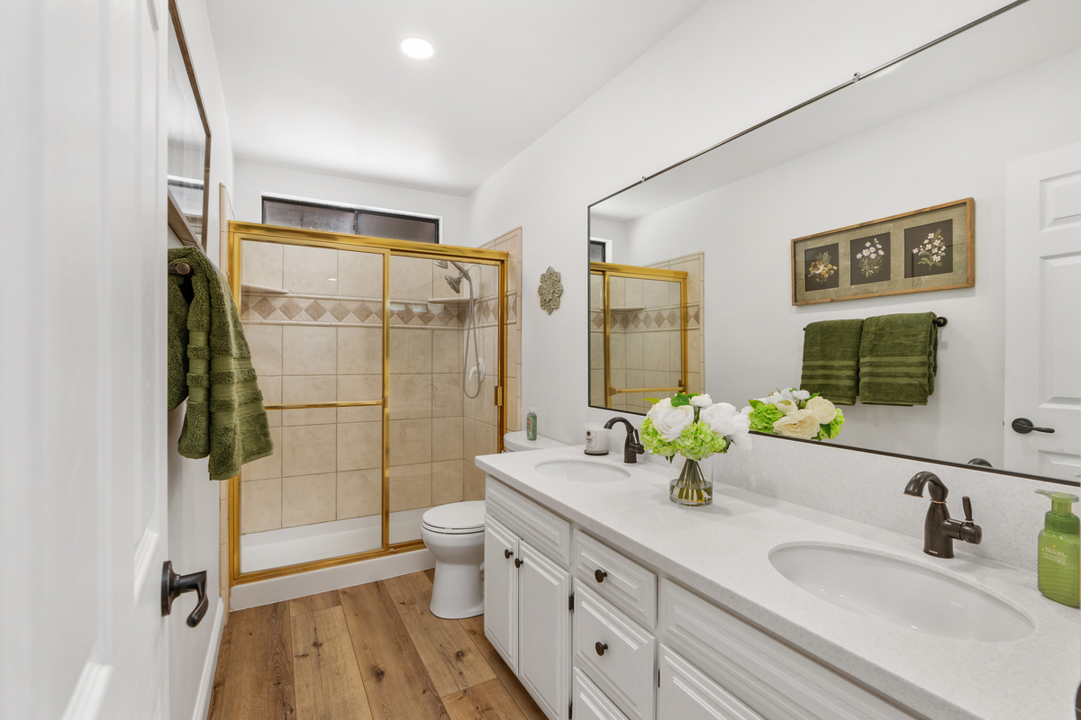 Updated bathroom with gold-framed glass shower enclosure