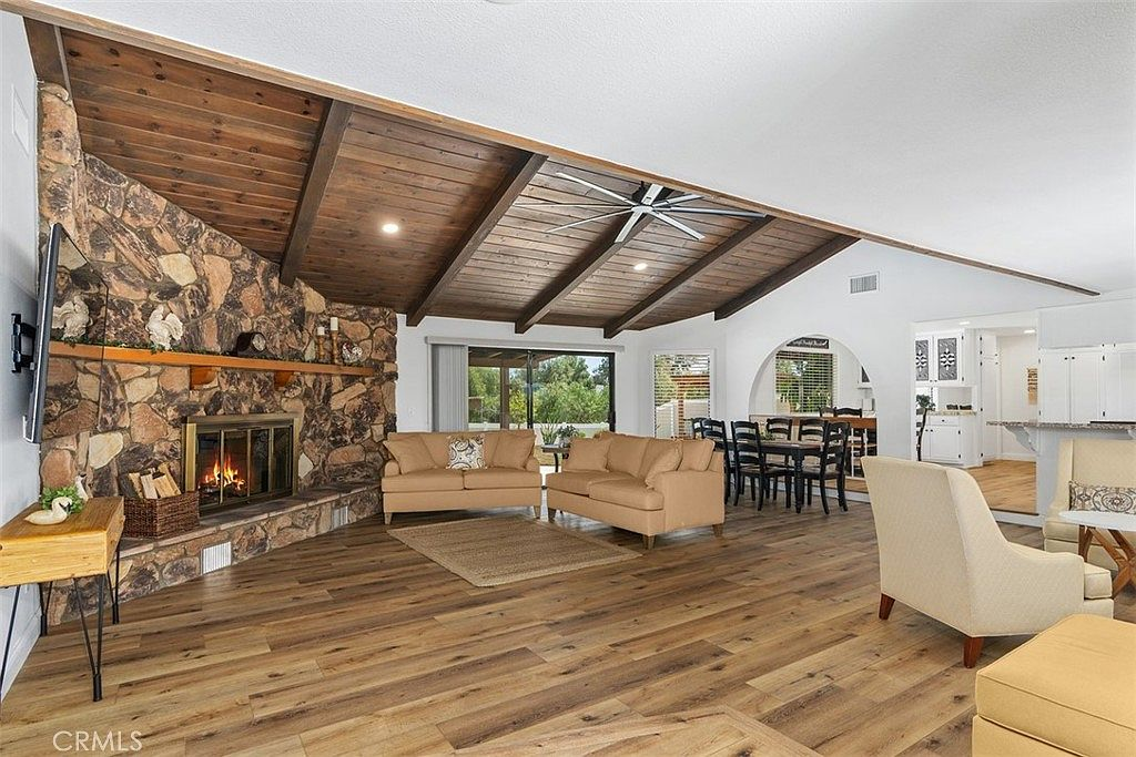 Open-concept living room with stone fireplace and wood beams