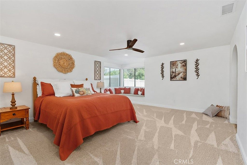 Primary suite with built-in window seating, soft carpet, and arched entry to en-suite bathroom